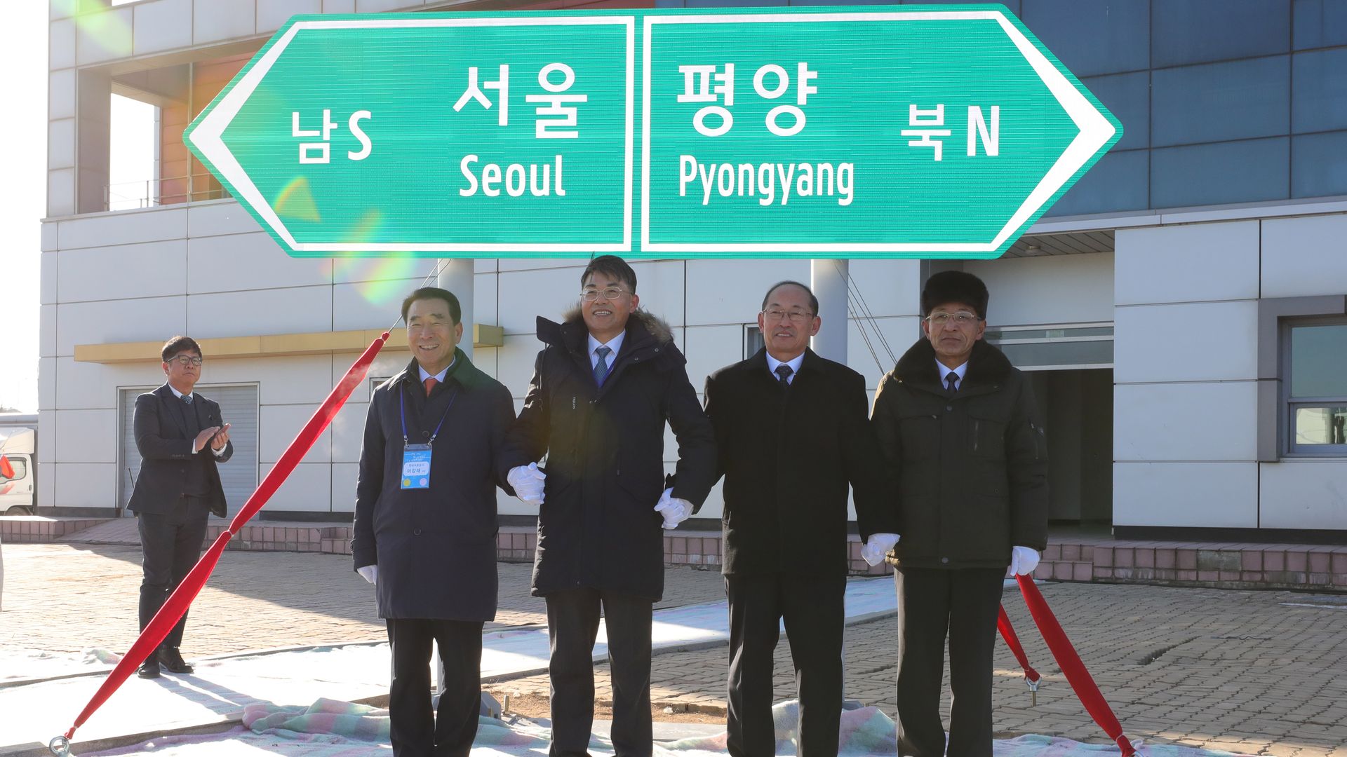 Officials from South and North Korea stand in front of a road sign in Kaesong, North Korea.
