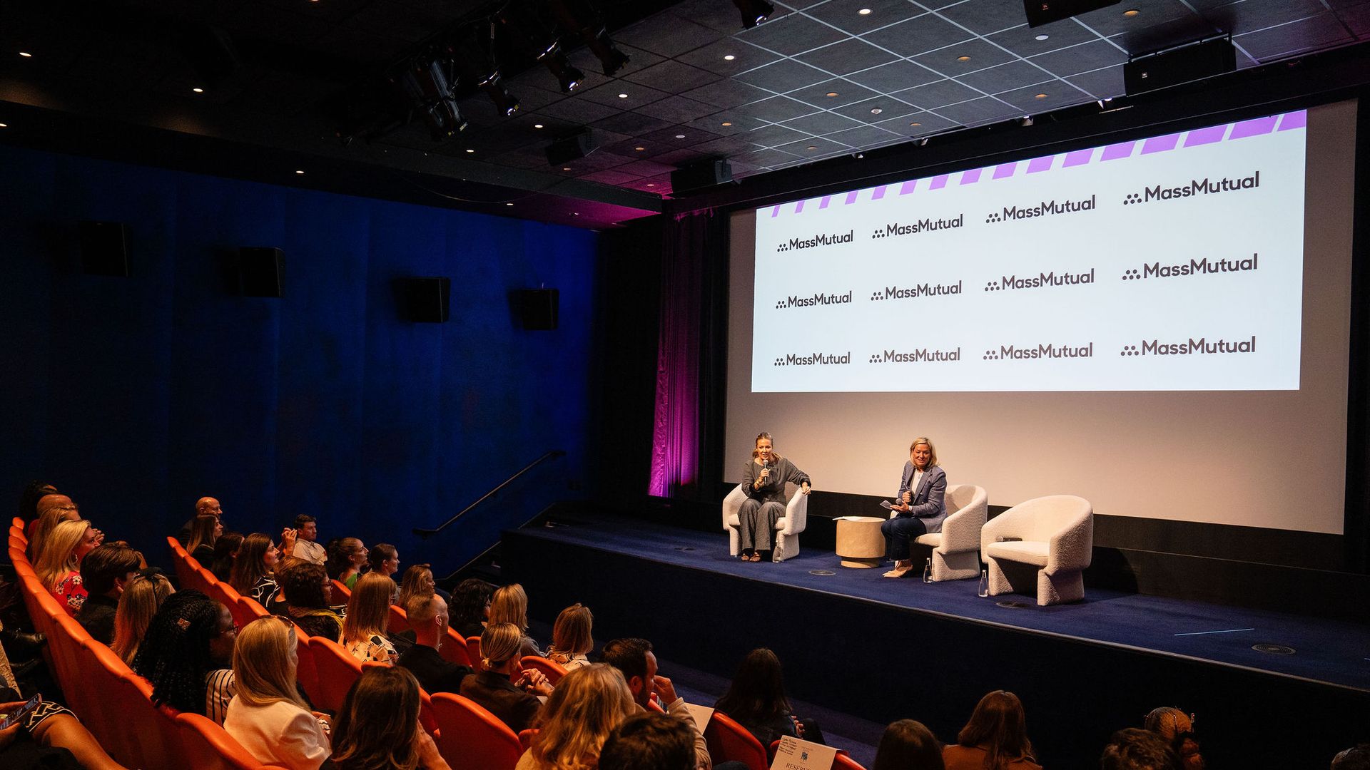 A speaker on a stage talking to an audience.