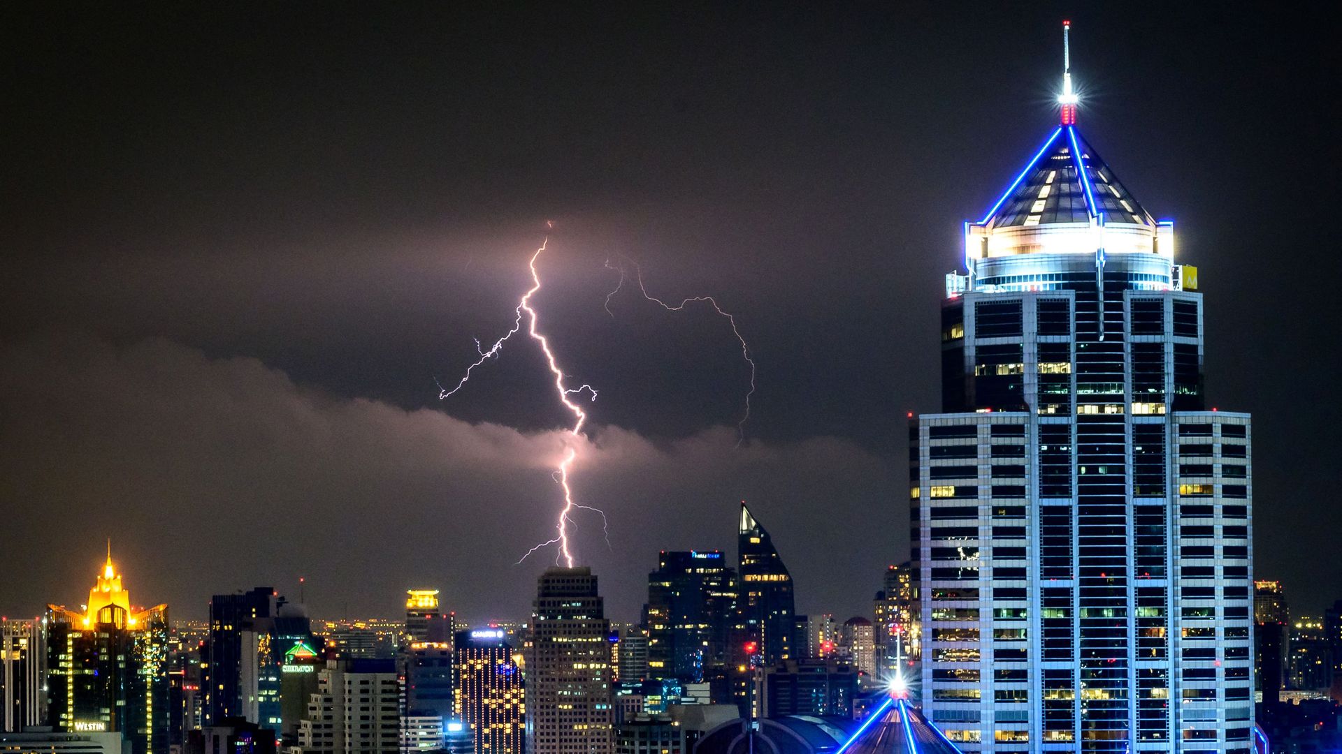 A lightning bolt above a night-time cityscape. 
