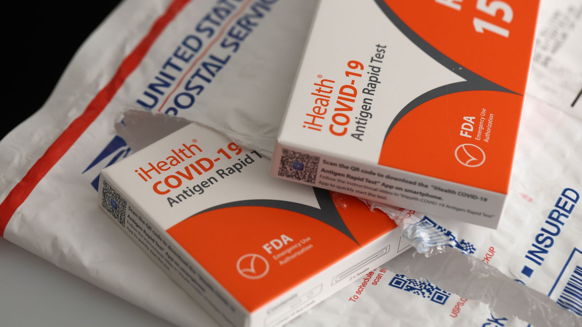 iHealth COVID-19 tests are on top of and inside a United States Postal pouch