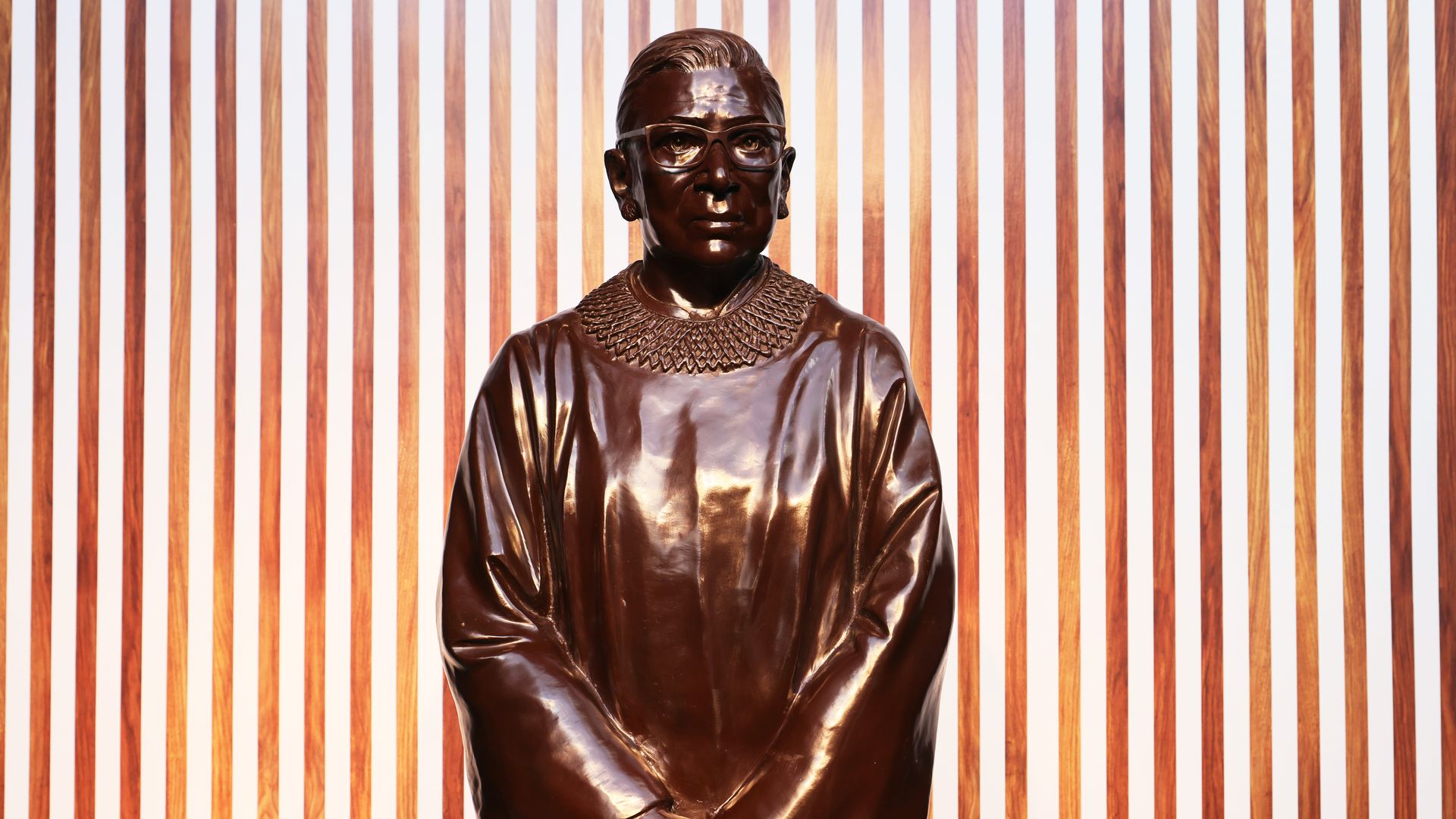 Photo of a bronze statue of Ruth Bader Ginsburg holding her linked hands in front of her