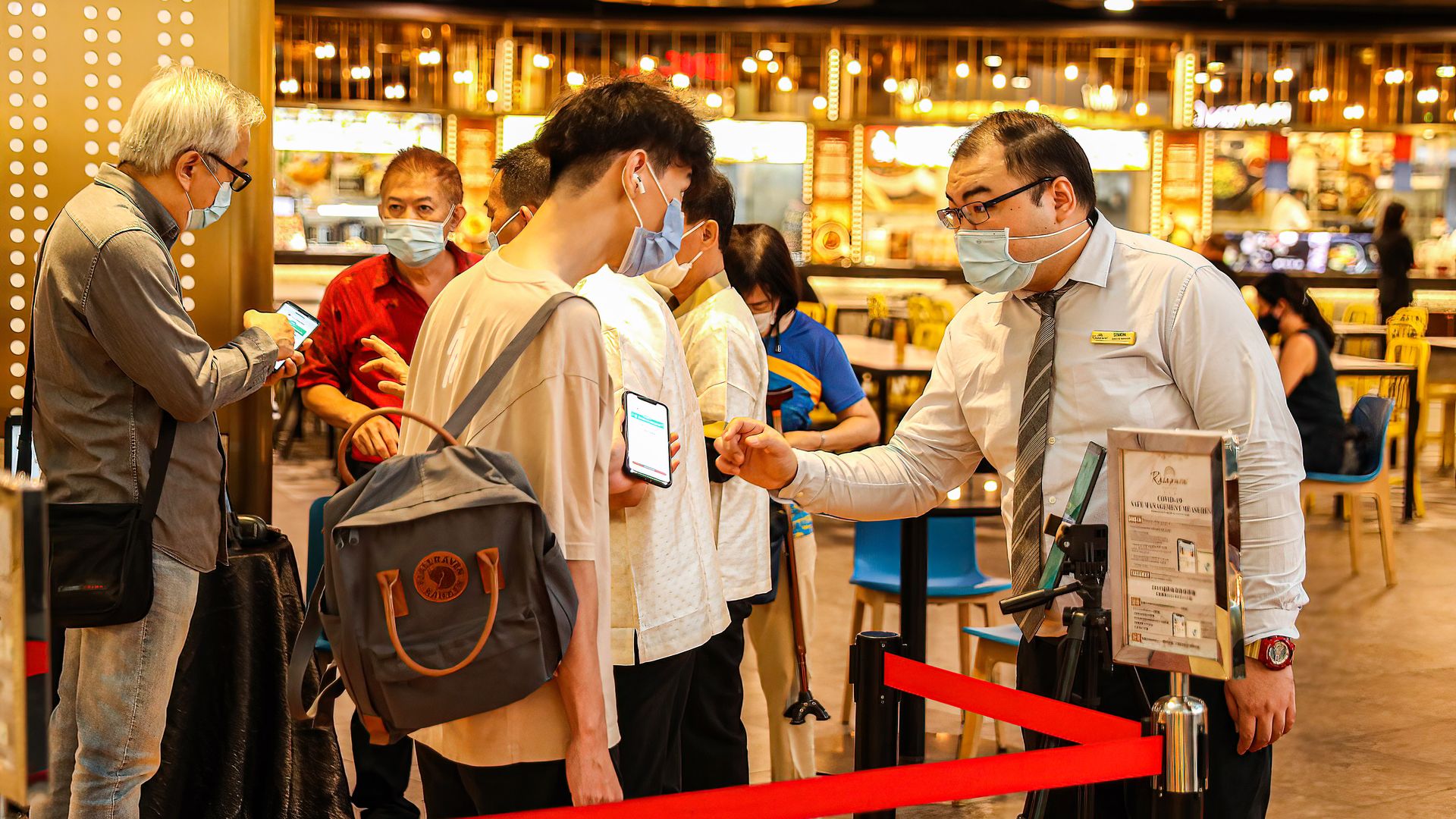 Staff at the food court verify a person's check in status on the TraceTogether app at Marina Bay Sands, Singapore