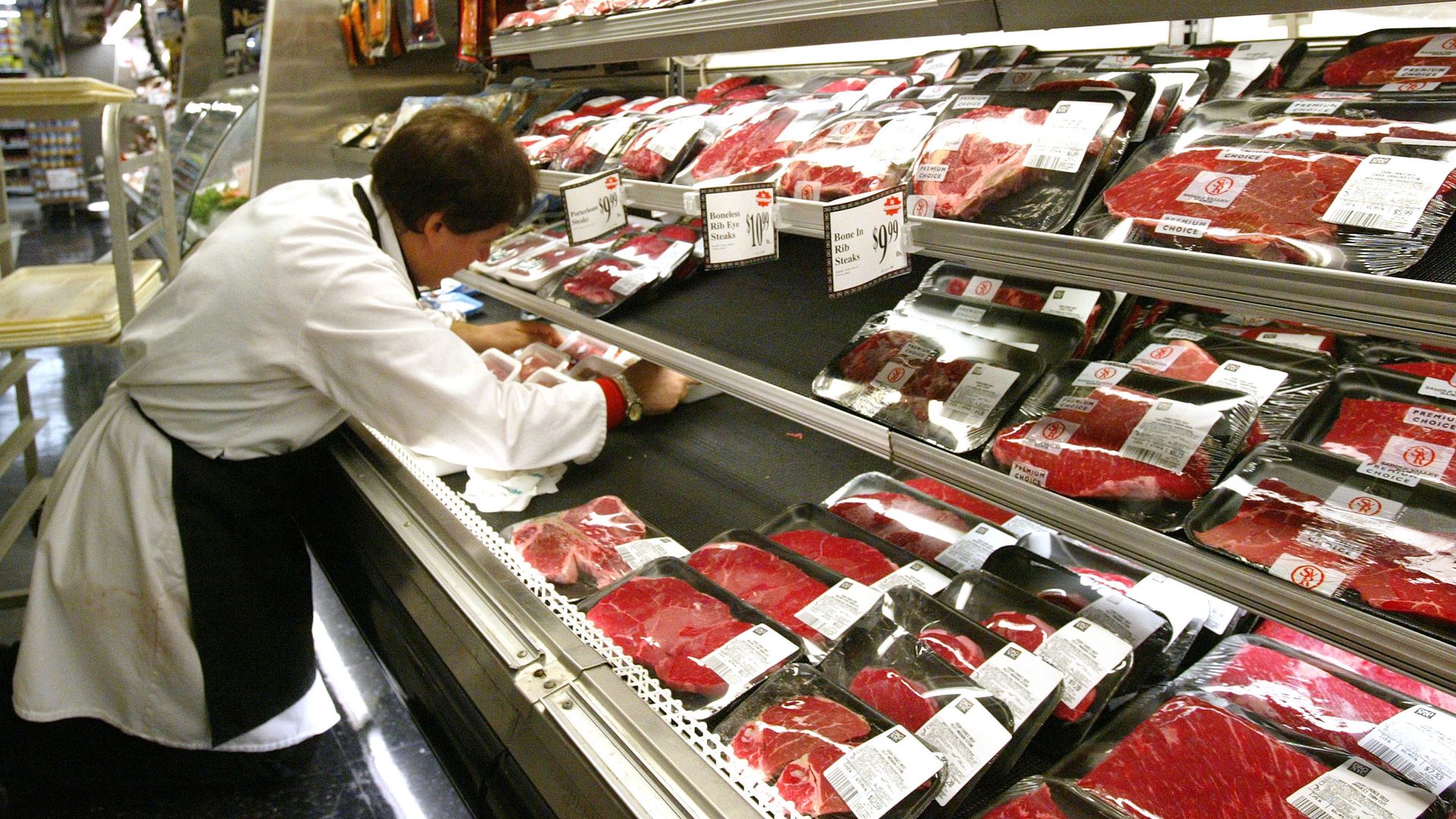 A butcher arranges meat products.