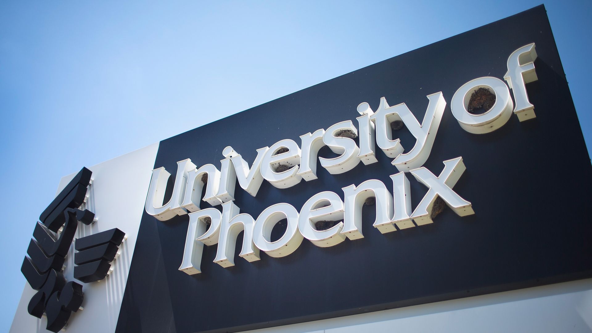 In this image, a campus sign reads "University of Phoenix" 