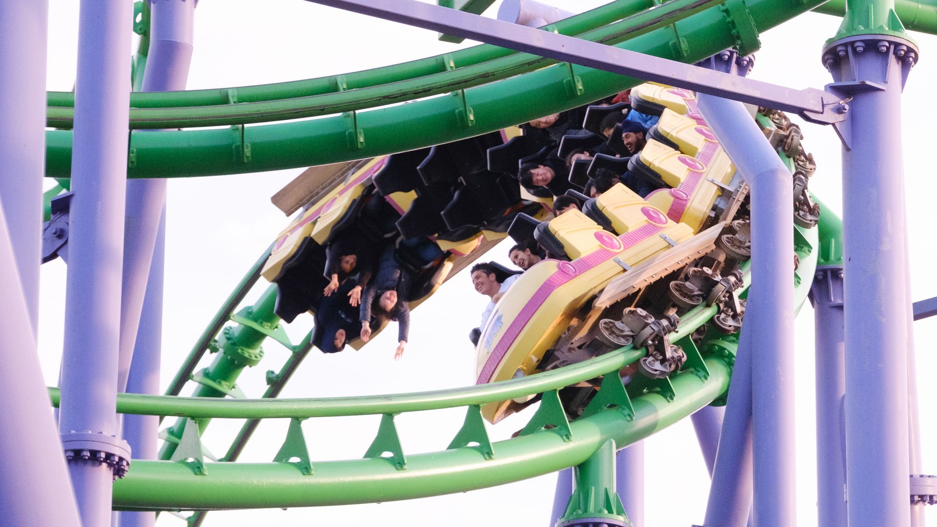 People riding a green and purple roller coaster