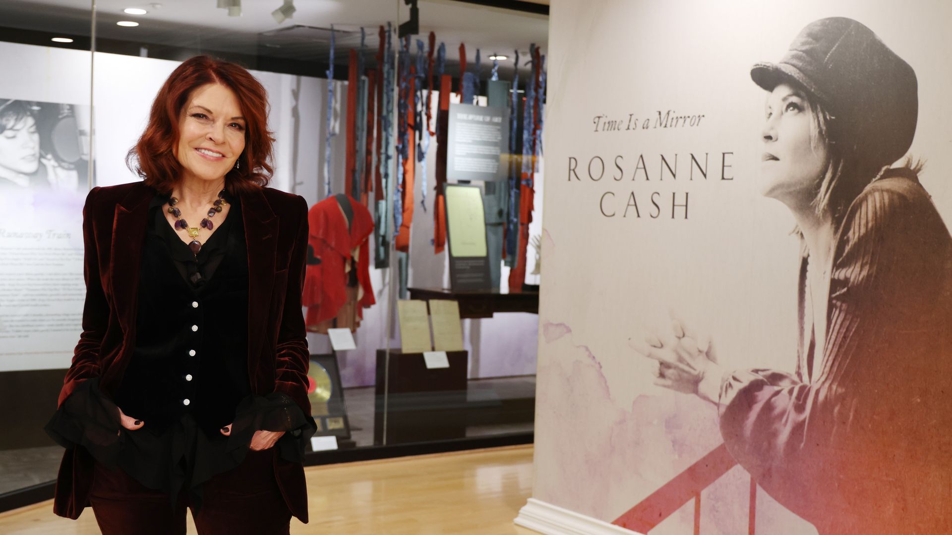 Rosanne Cash posing in front of a museum exhibit dedicated to her.