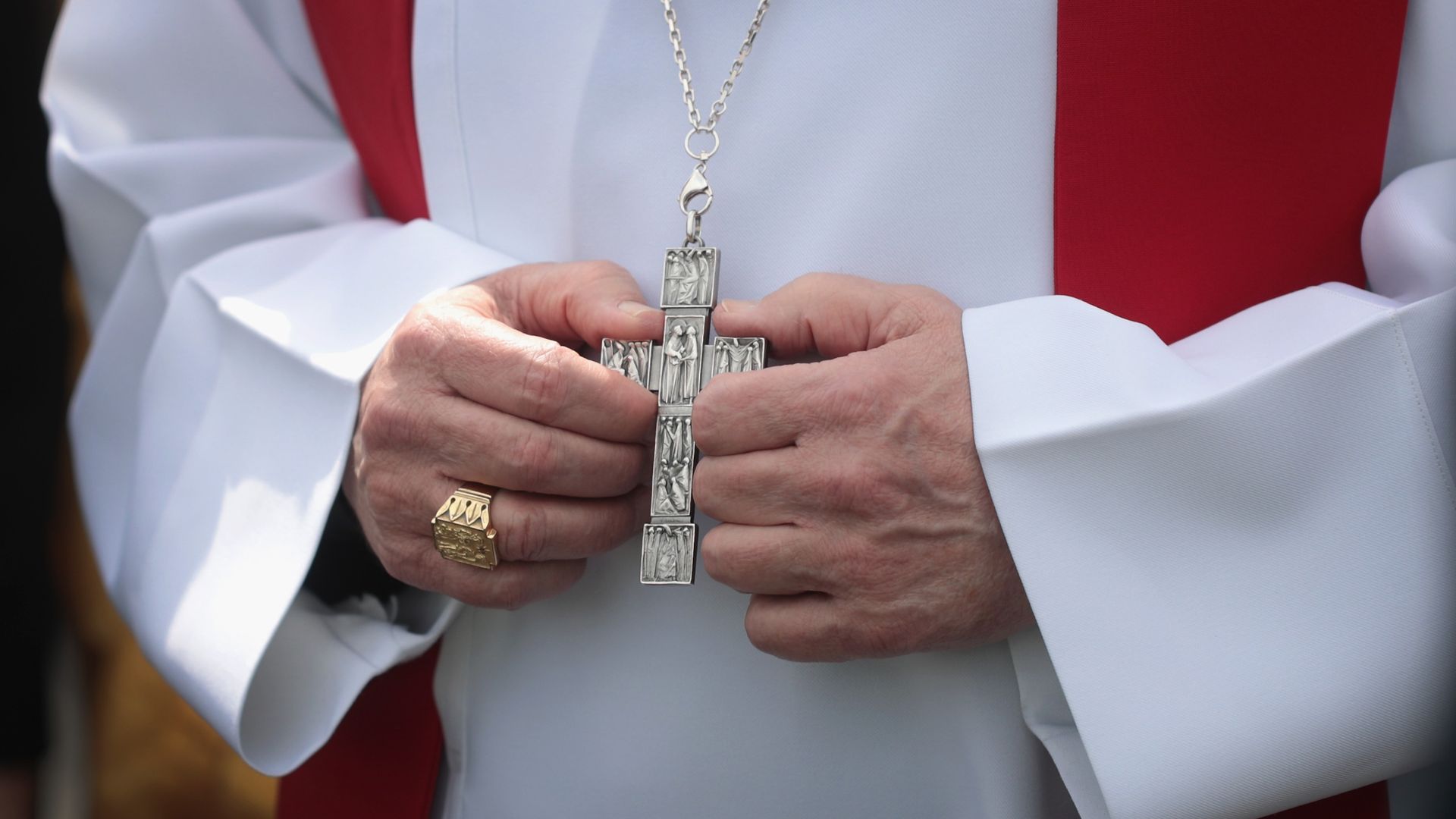 A close-up of a Cardinal's hands holding a cross.