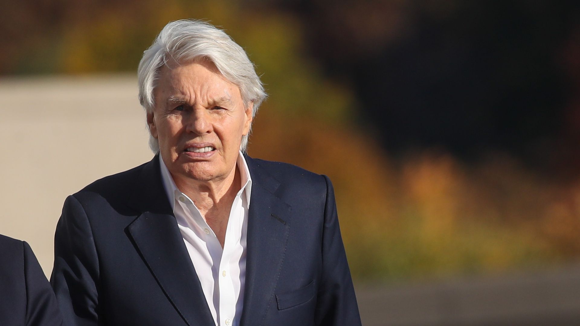 Mike Jeffries walks outside. He wears a dark suit and white shirt 