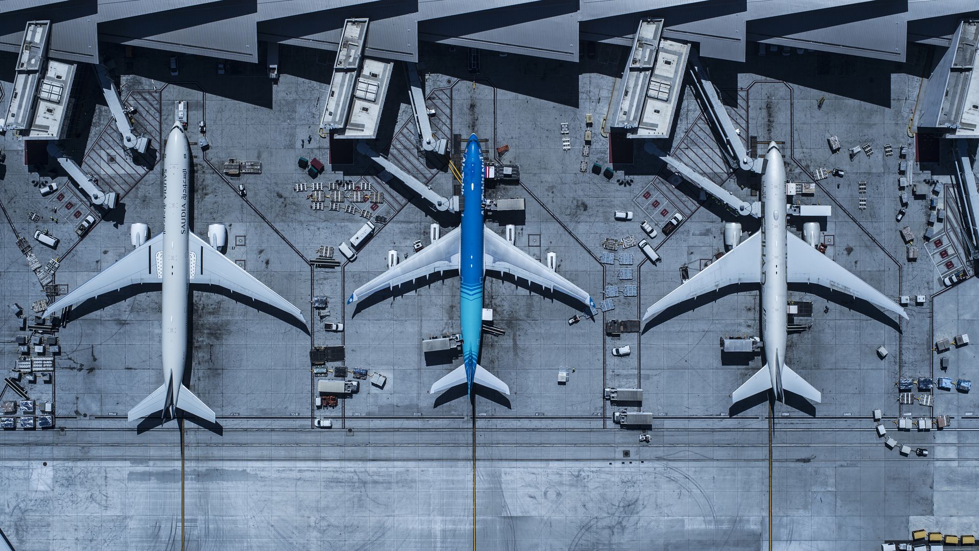 Three airplanes docked at airport terminals