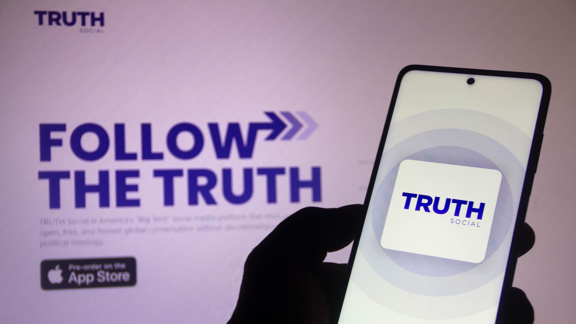 Photo illustration of the Truth Social logo on a computer screen and cell phone screen