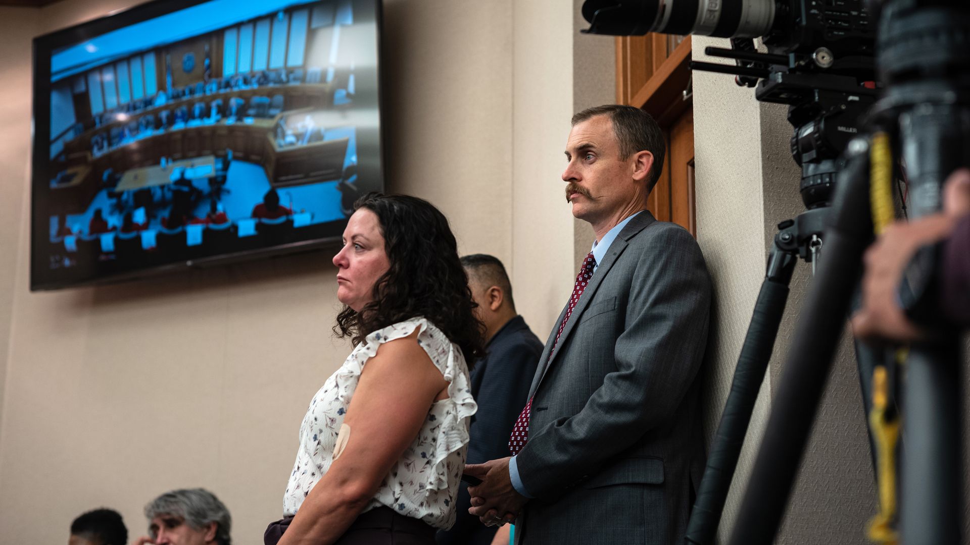 A mustachioed man looking on at a hearing 