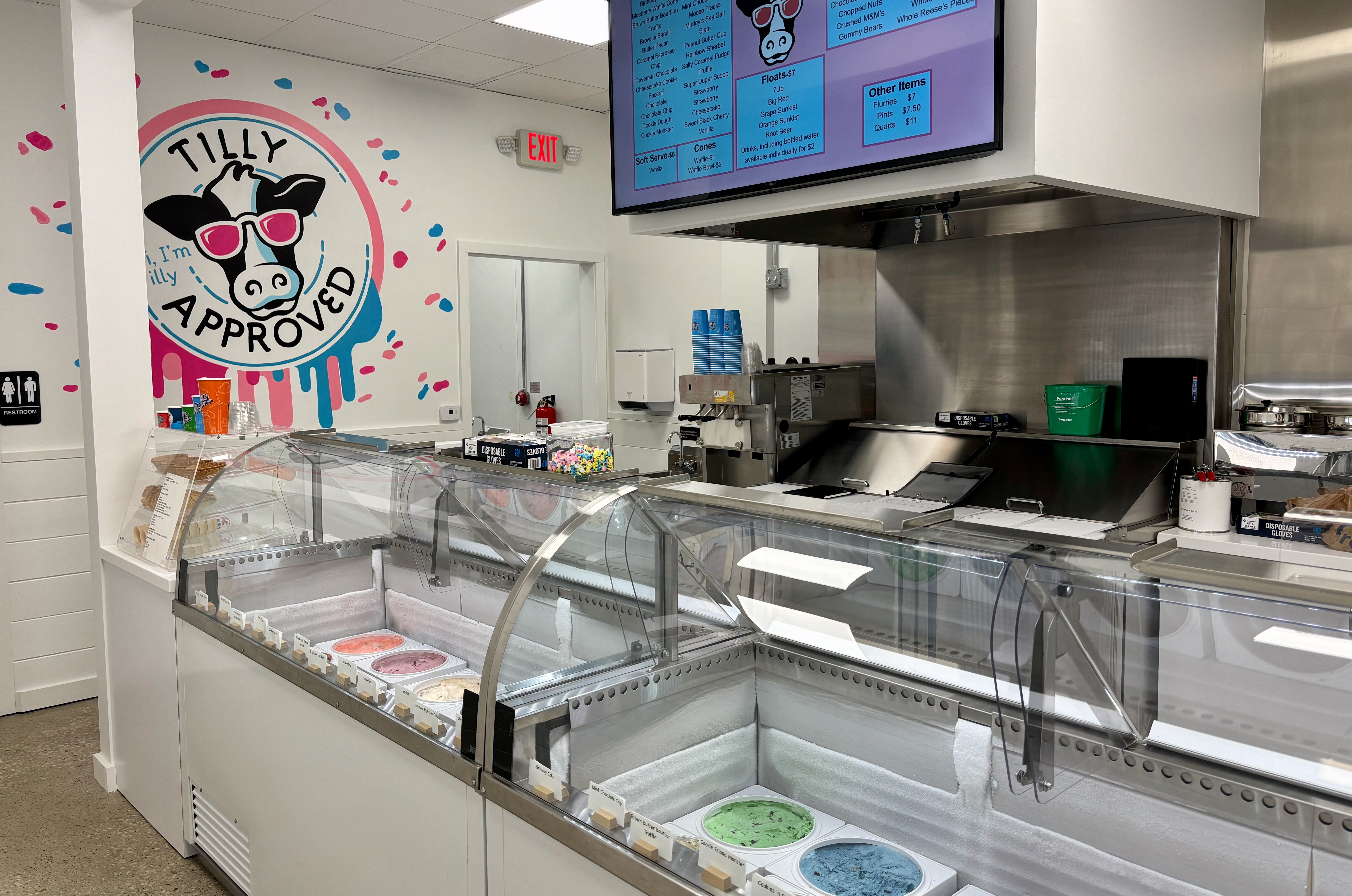 An overview of the ice cream bar at Toft's Grand Scoop, with a logo of a cow in sunglasses that says "Tilly approved" painted on the wall