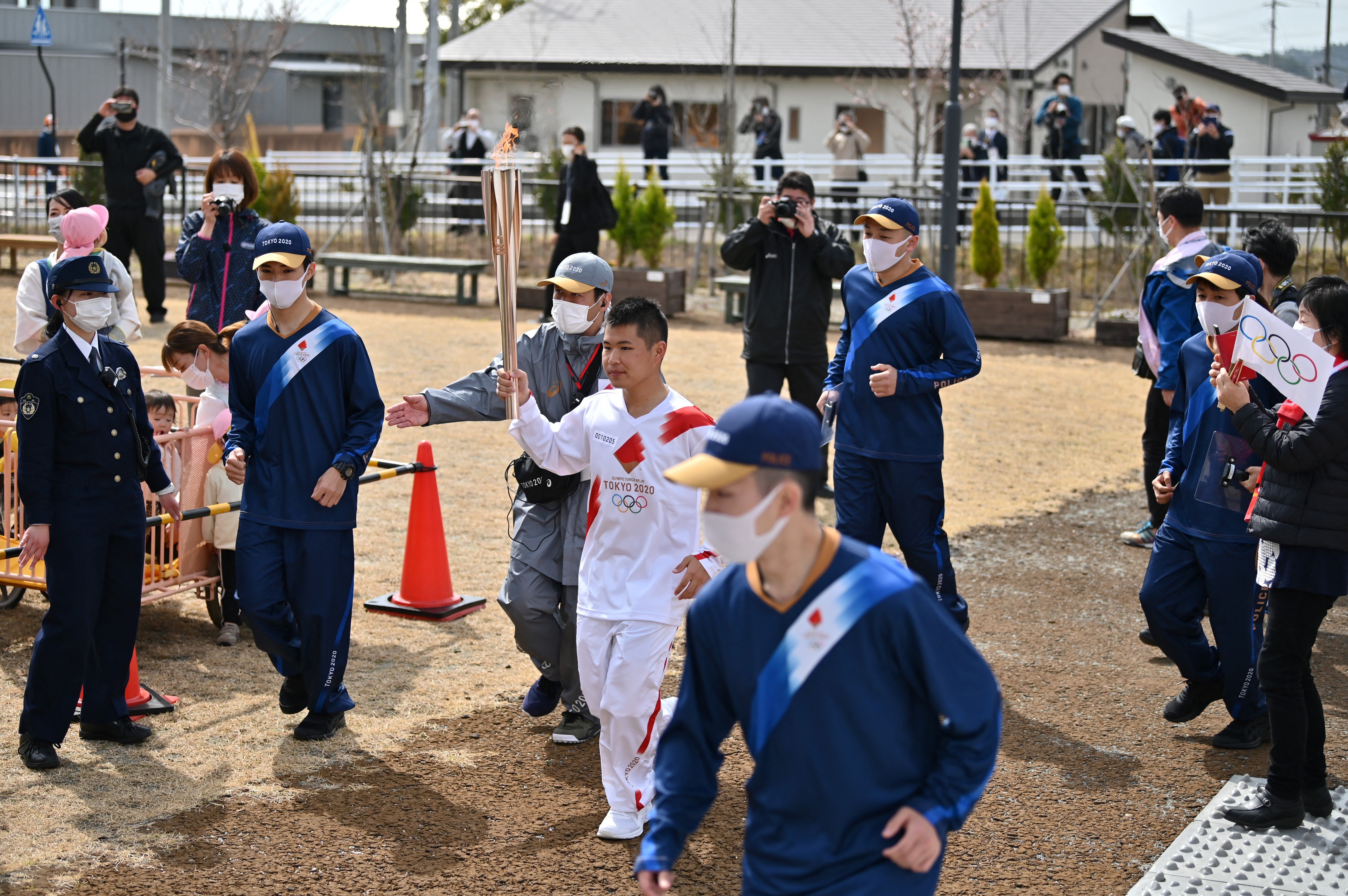 An athlete carries an Olympic torch during the first day of Tokyo 2020 Olympic Games torch relay in the town of Naraha, Fukushima Prefecture on March 25