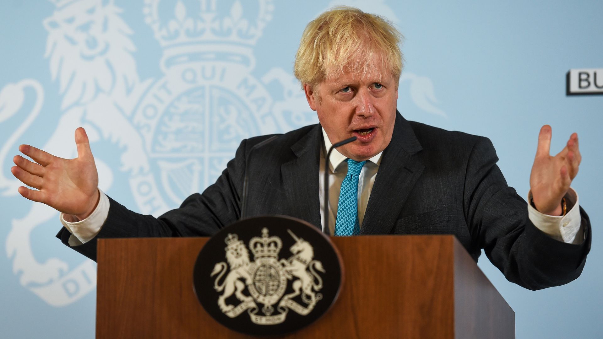 Boris Johnson stands in front of a podium 