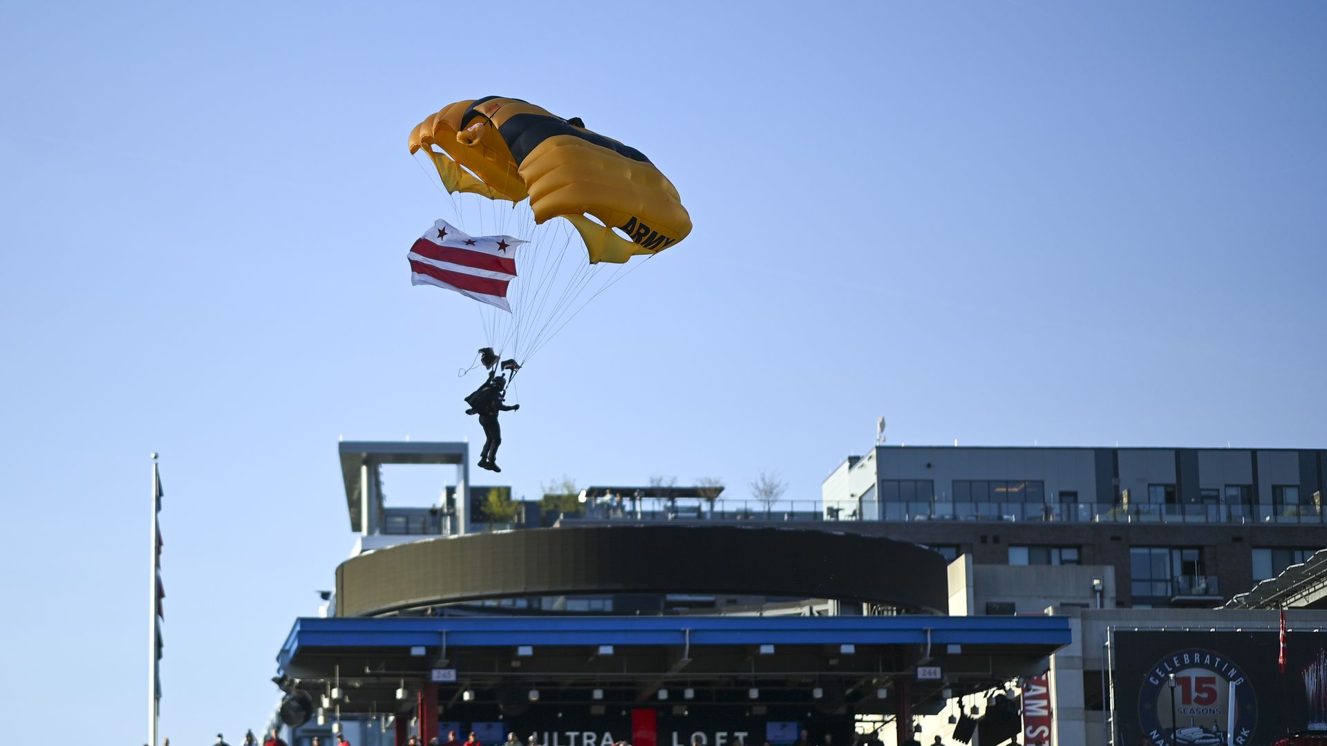 Photo of a person parachuting into a large stadium filled with people
