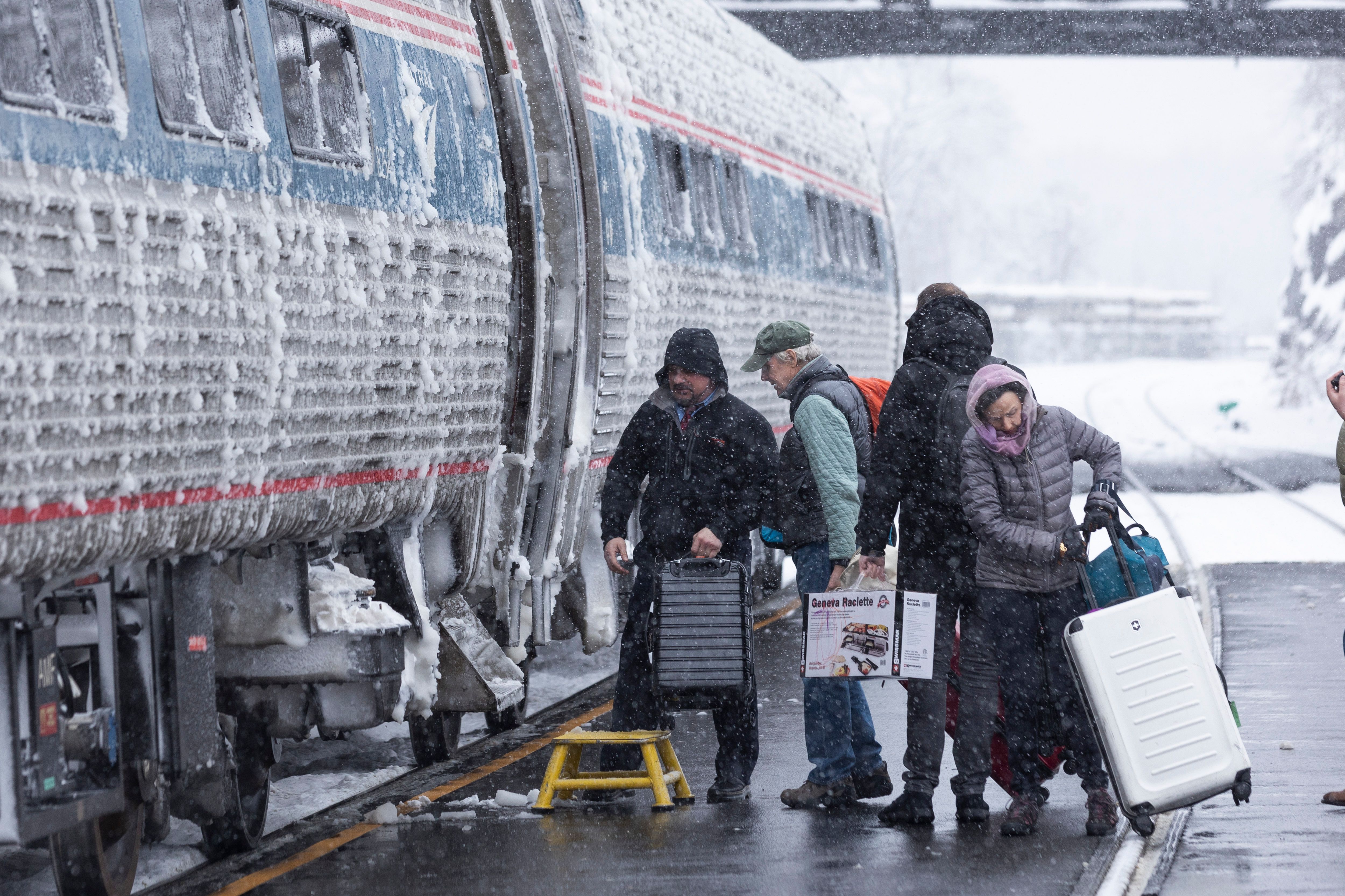 Travelers board an Amtrak train during a storm in Hudson, New York, US, on Sunday, Jan. 7, 2024. Hundreds of flights have been grounded across the US from a pair of winter storms that left more than a foot of snow in New York's Hudson Valley and sparked blizzard warnings across the Great Plains. 