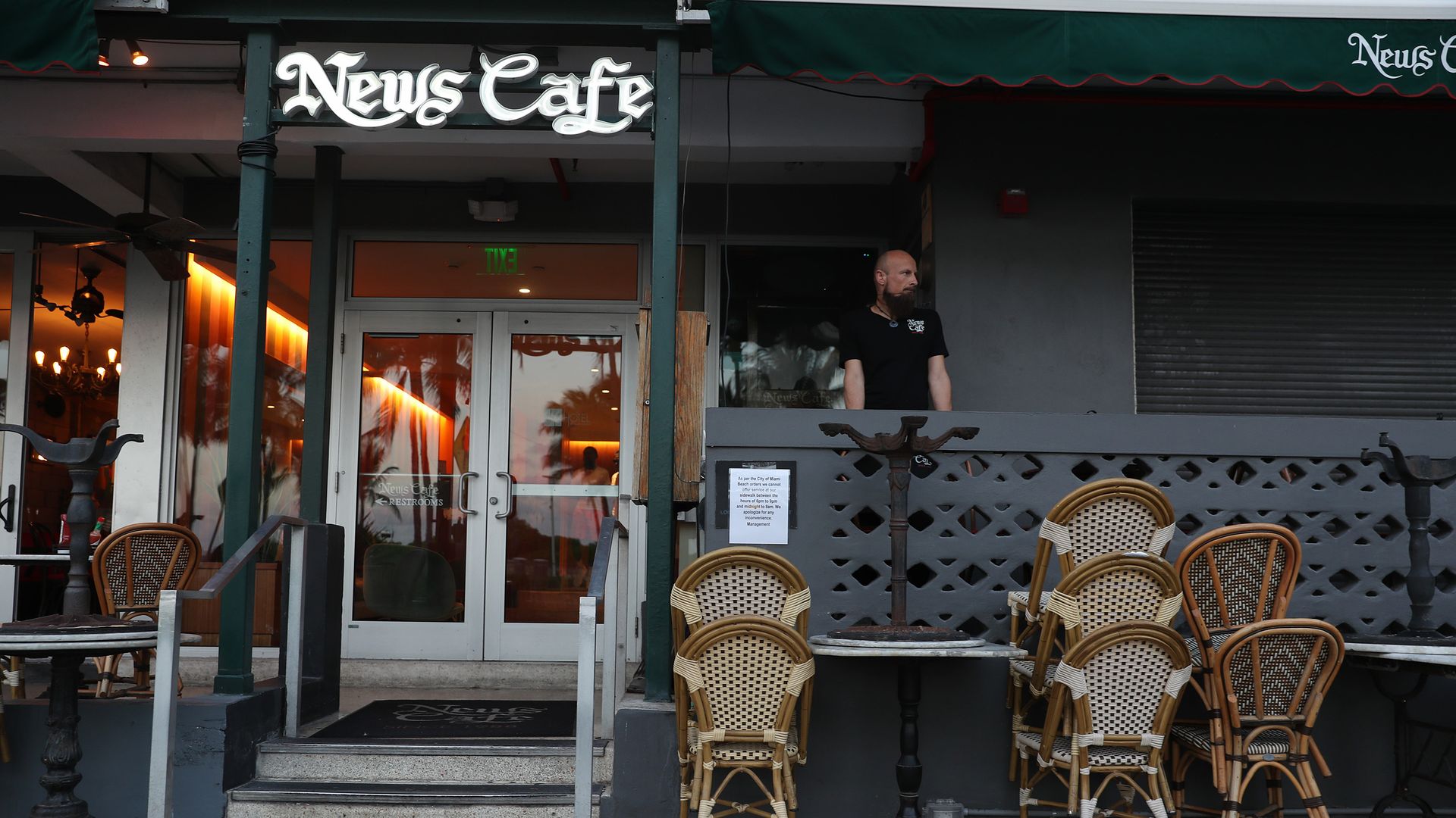 An employee of News Cafe waits outside for customers during the COVID-19 pandemic.