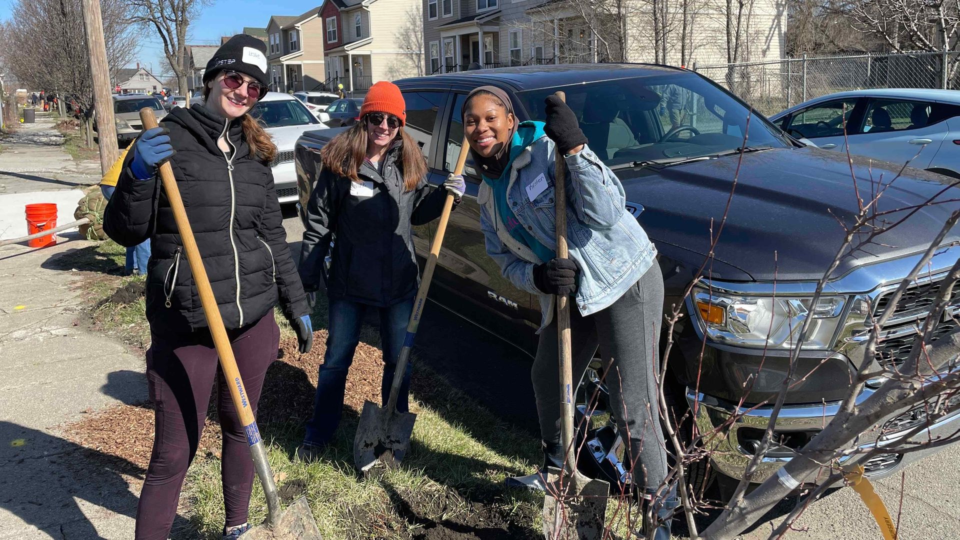 Volunteers planting trees for the Greening of Detroit nonprofit holding shovels 