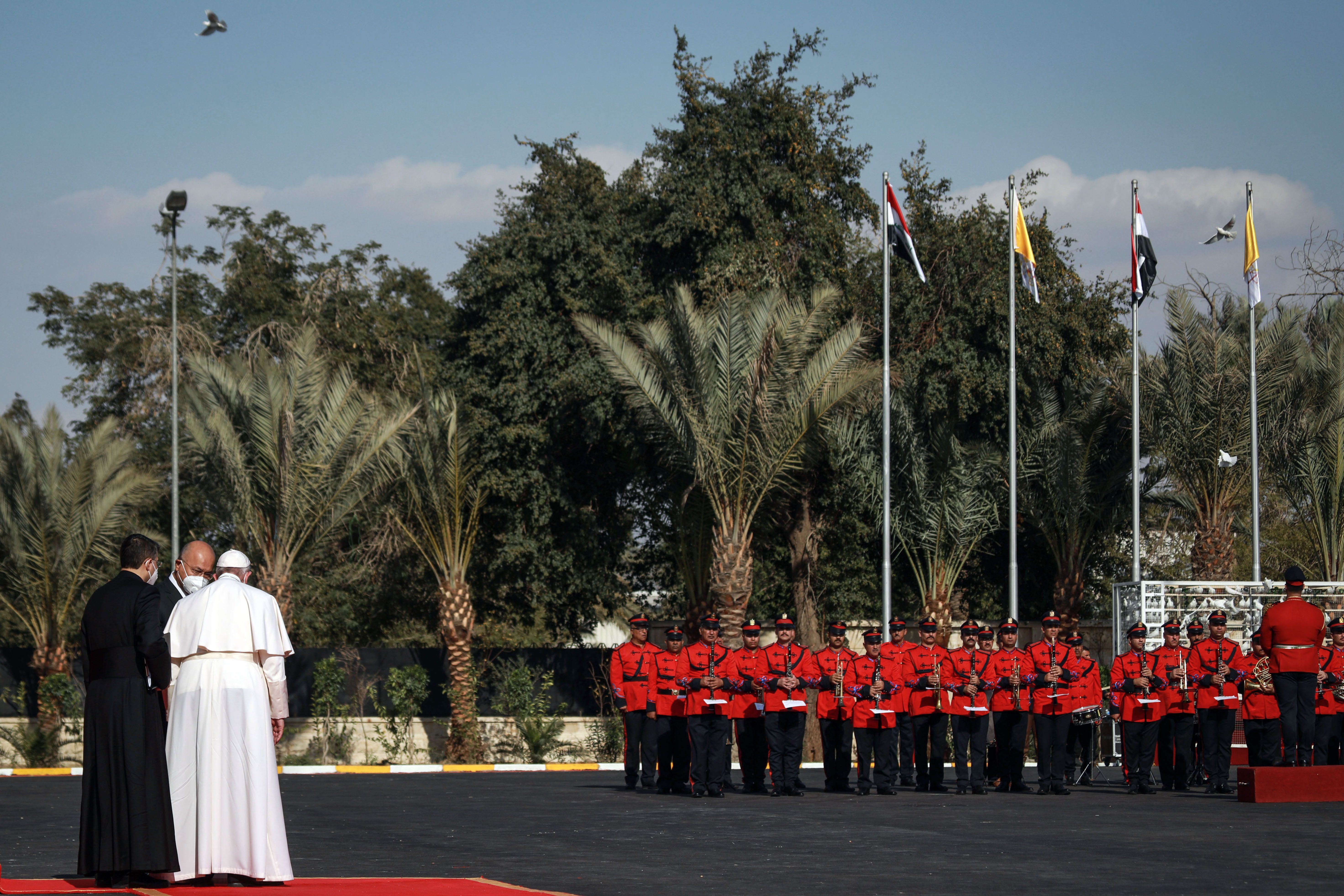 Photo of the Pope and Iraqi President Barham Saleh  looking at an honour guard