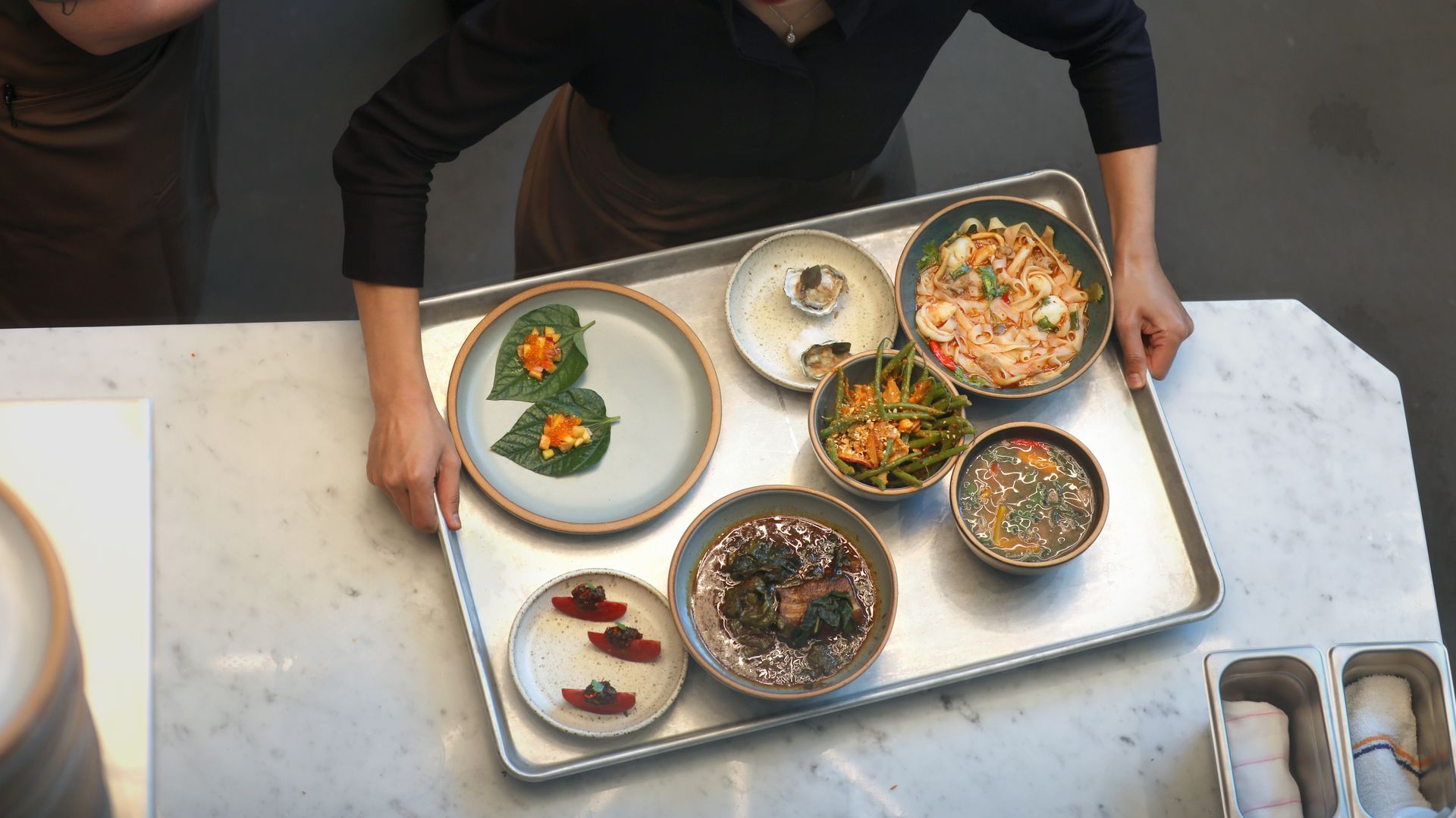Photo of a person picking up a tray of Thai dishes