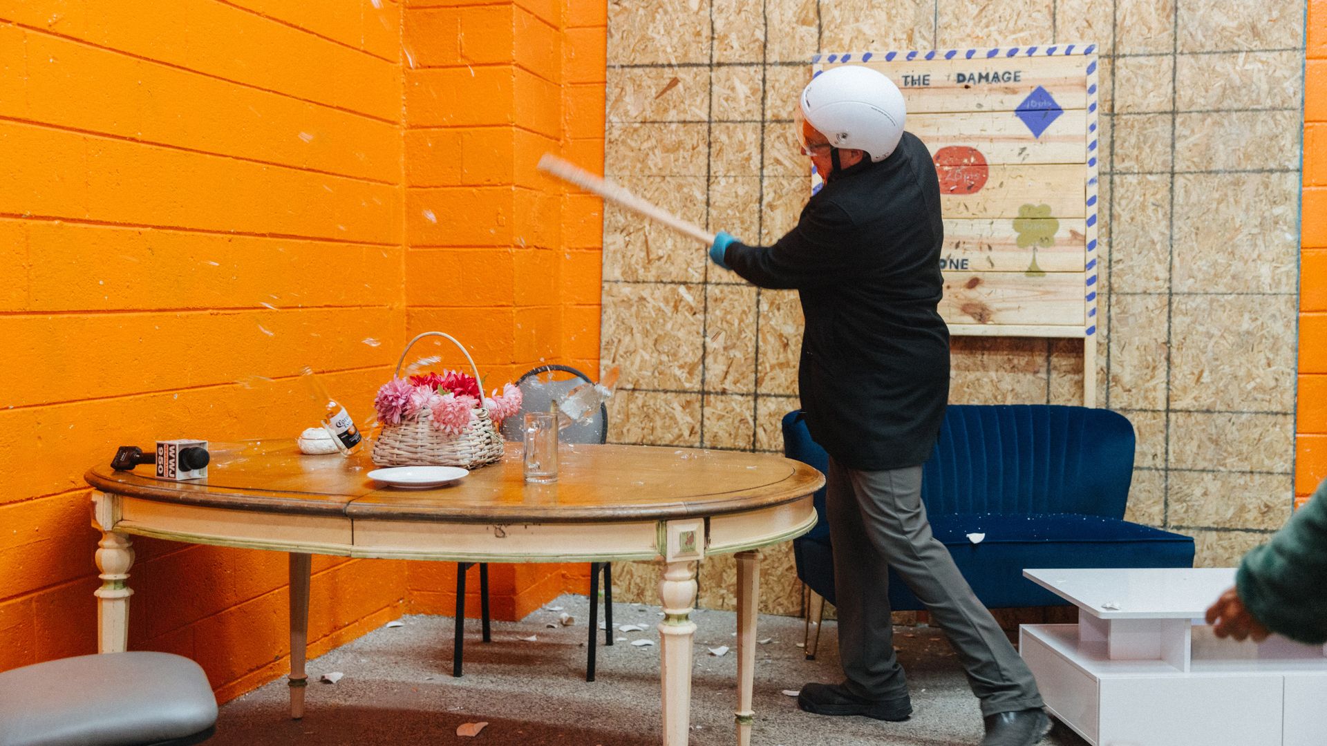 A person in a helmet breaks glass with a bat.