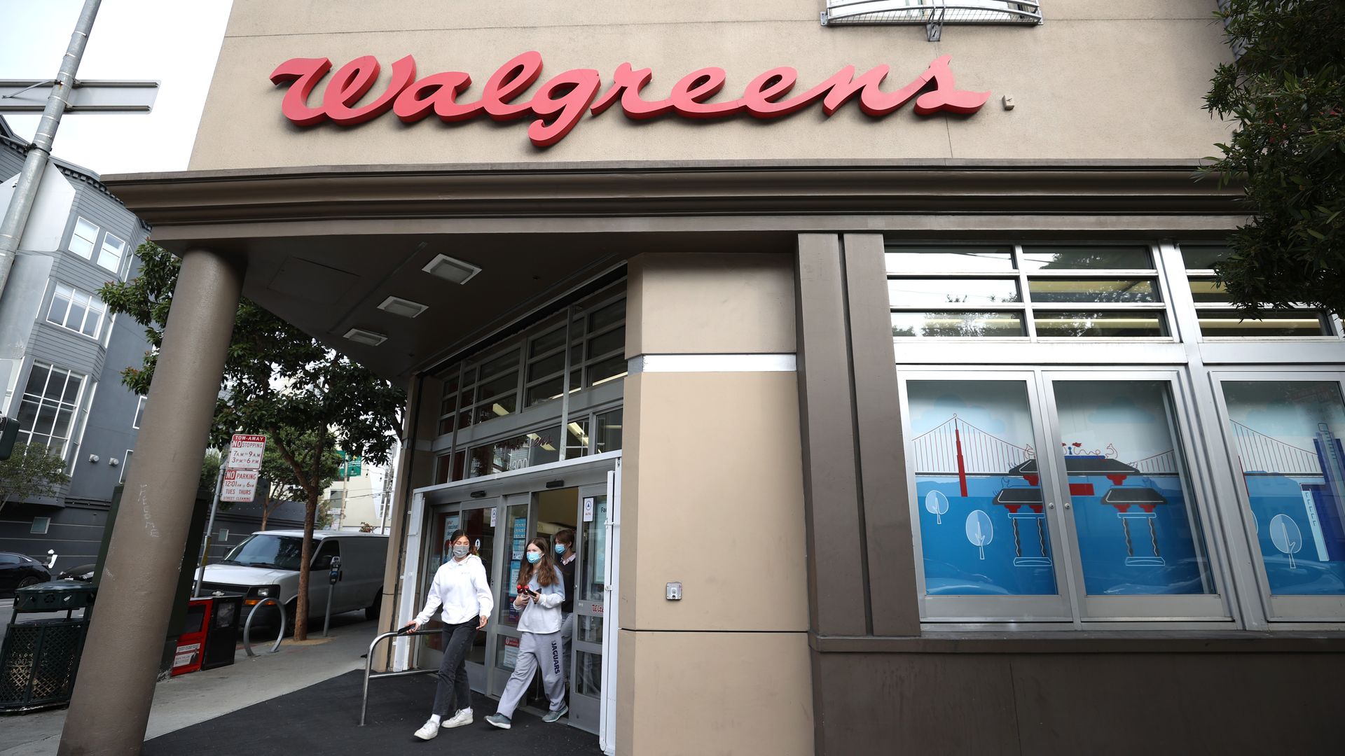 Two people walk out of a Walgreens drugstore.