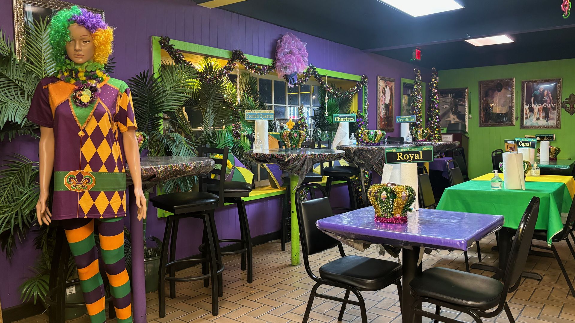 A mannequin and tables intricately decorated in Mardis Gras colors  (purple, yellow and green)