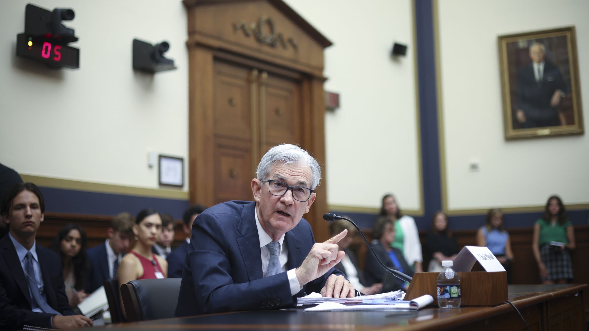 A man in a suit testifies at a wooden table