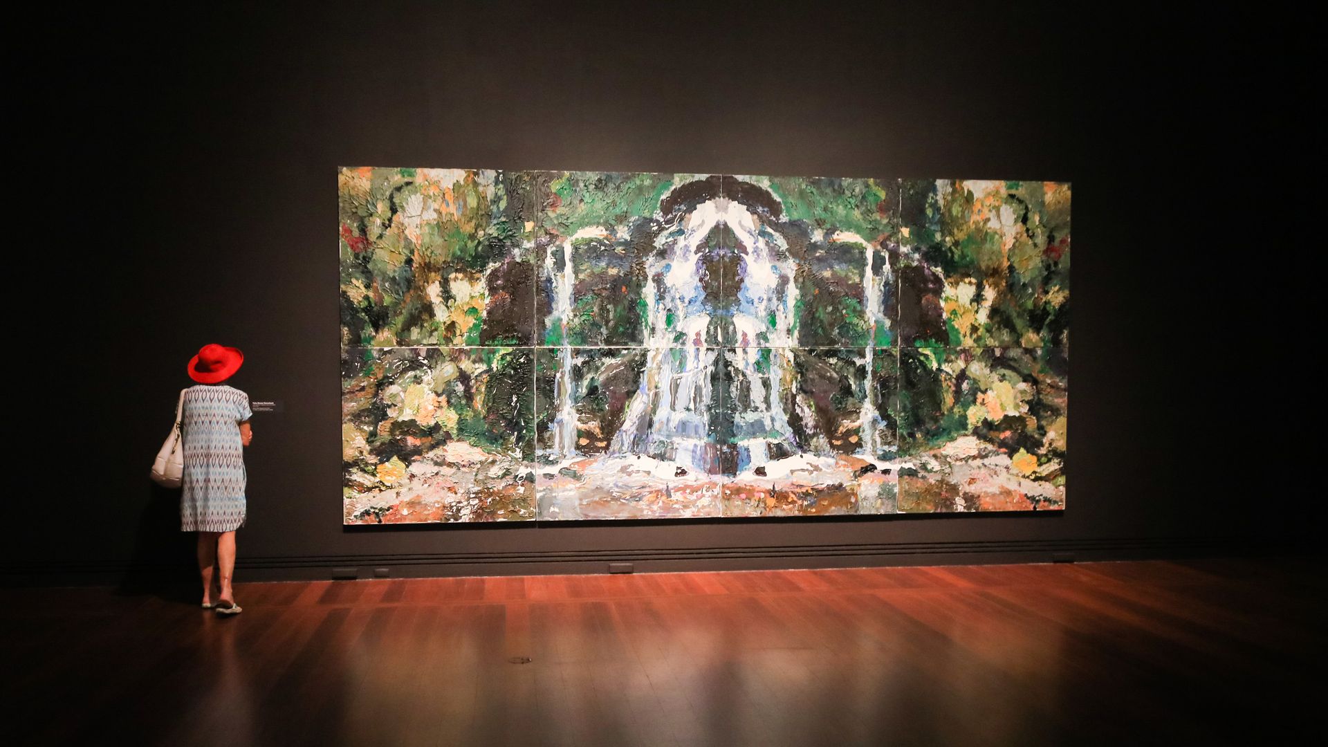 A woman stands in front of a large painting