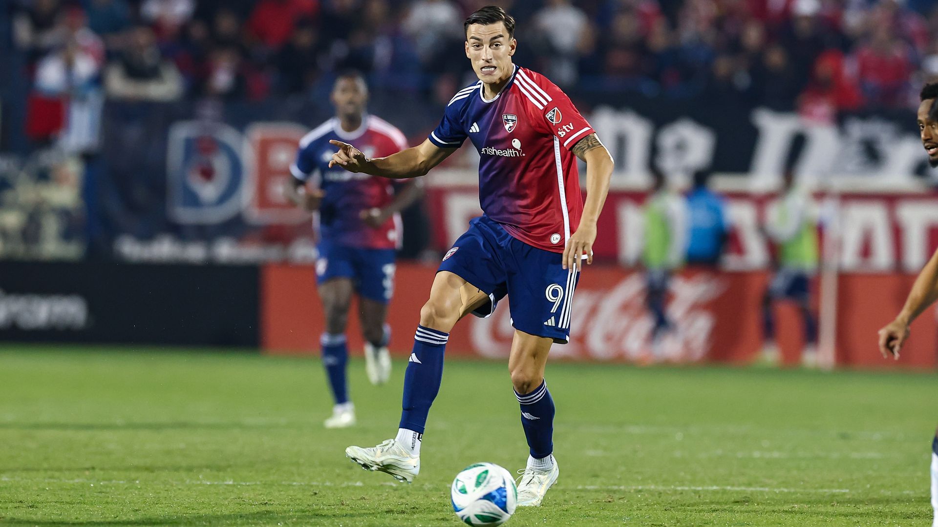 FC Dallas forward Petar Musa passes the ball up the field at a soccer match.