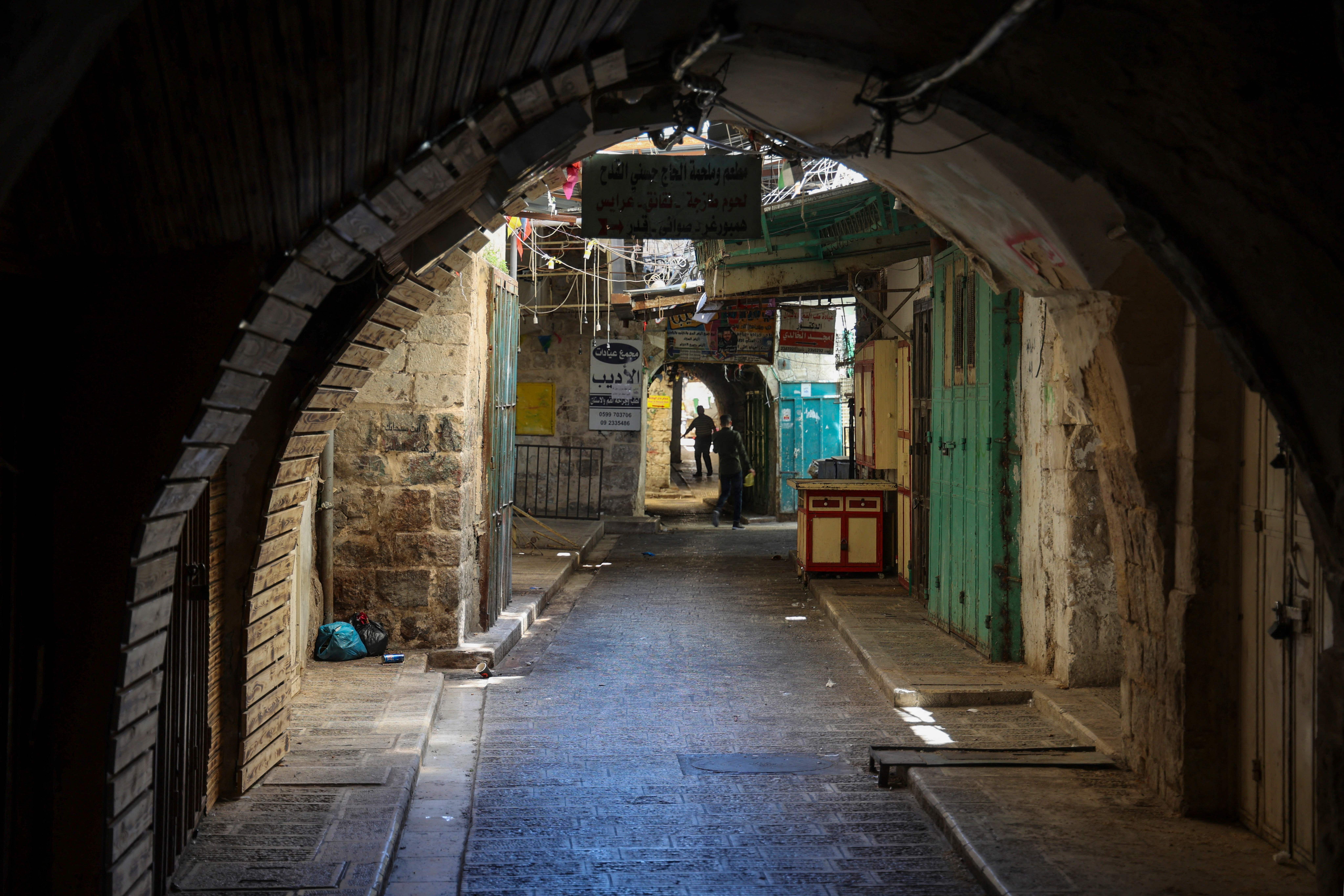 Palestinians walk past shuttered stores in the occupied West Bank city of Nablus as a general strike is observed in solidarity with Gaza and Jerusalem. 