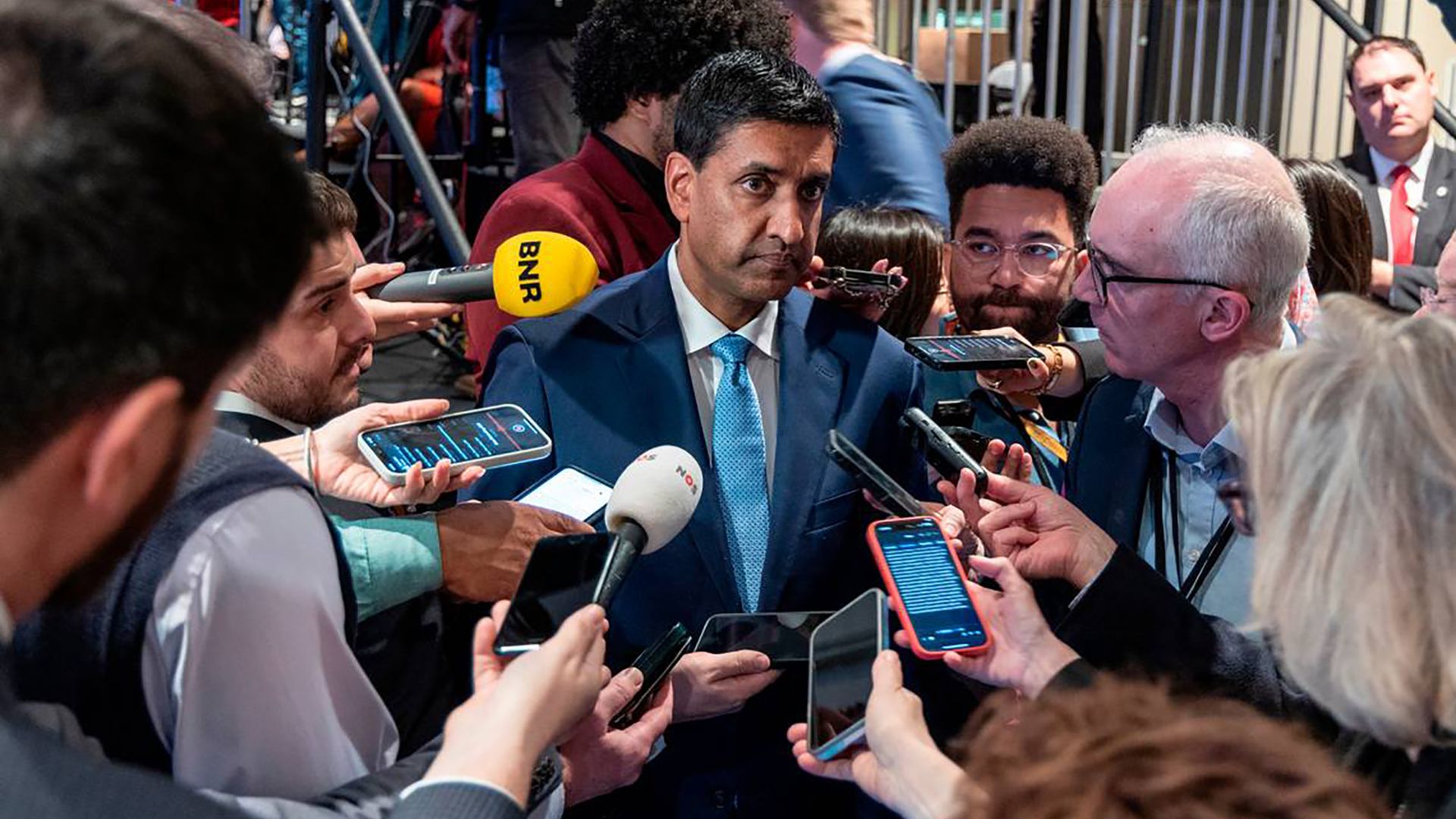 Rep. Ro Khanna, wearing a blue suit and surrounded by reporters.