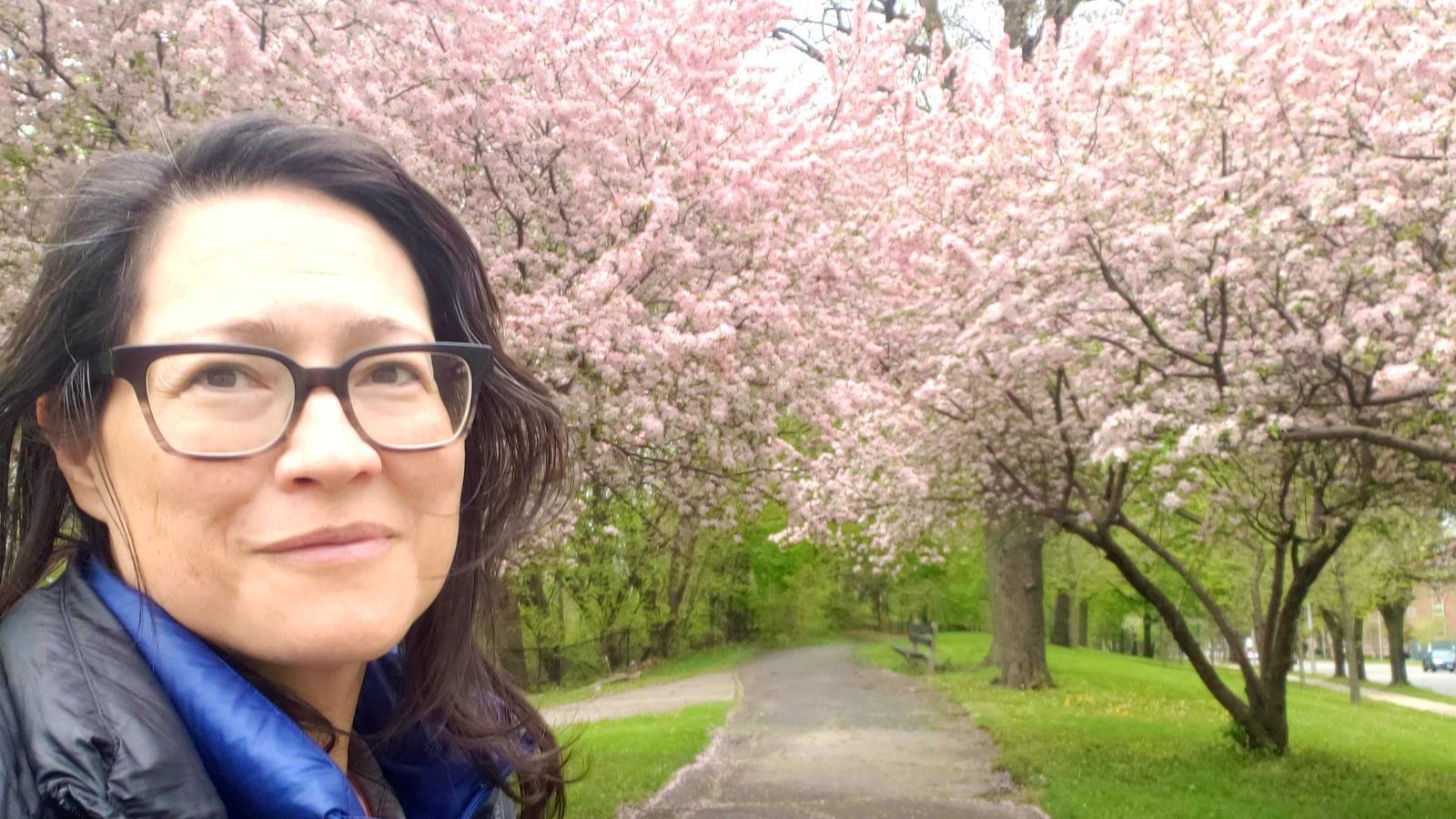Axios Chicago reporter Monica Eng poses outside of Columbus Park, near cherry blossoms.