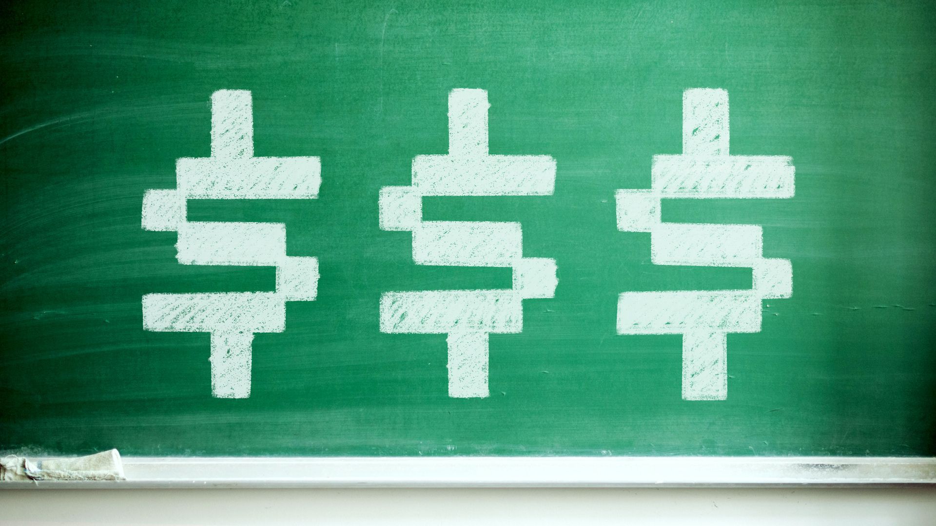 Illustration of a chalkboard with three dollar signs drawn on it.