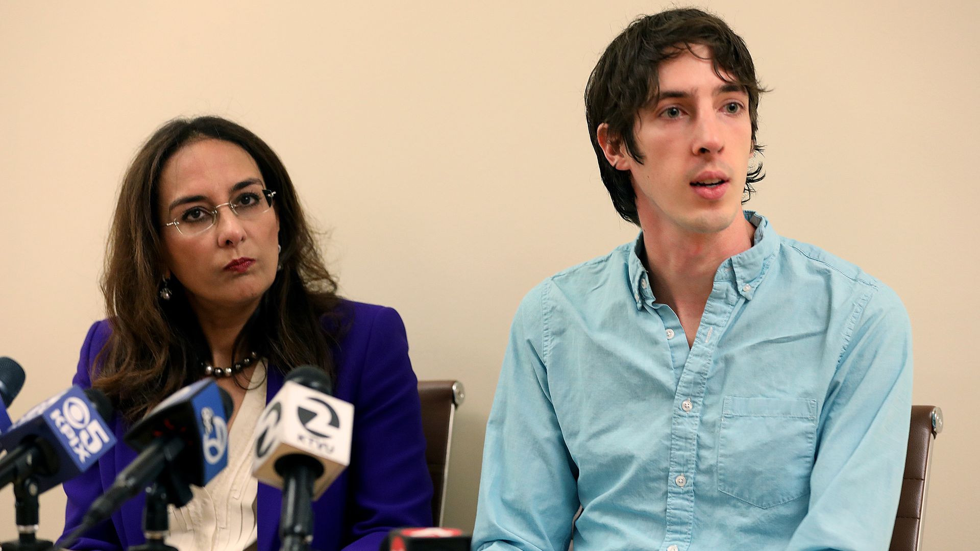 In this image, Jason Damore sits in front of news microphones.
