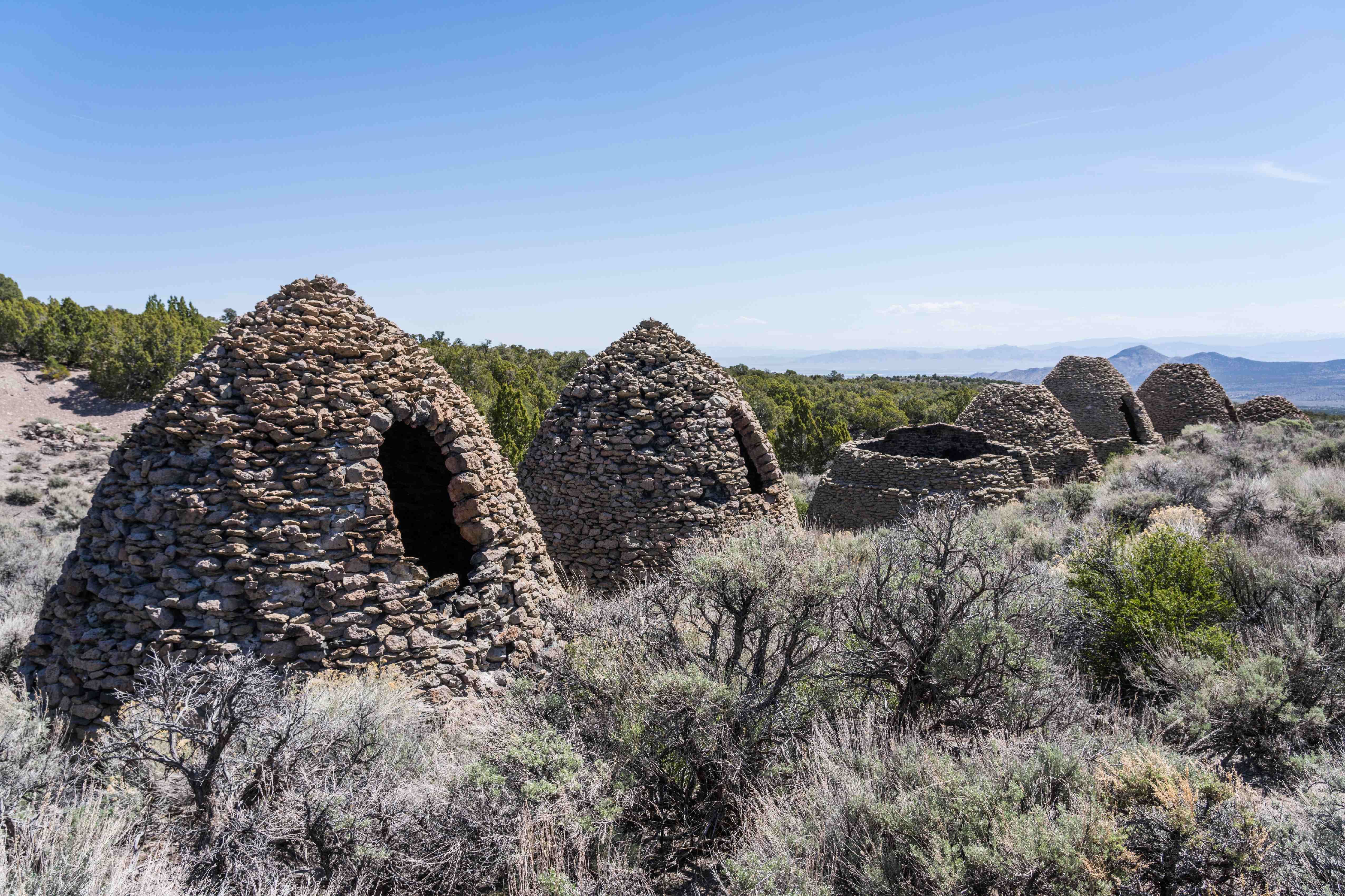 Stone kilns shaped like beehives stand in sagebrush landscape.