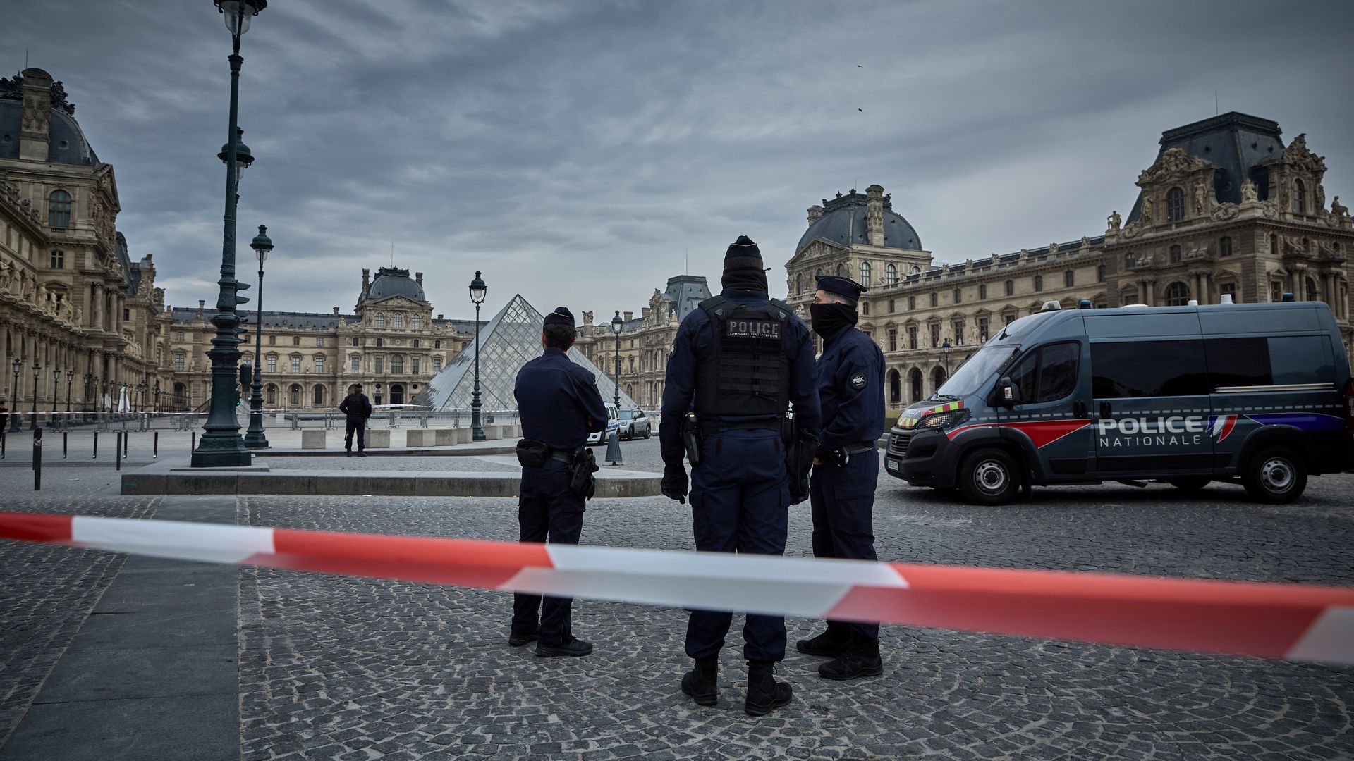French police stand at the Louvre entrance following a reported robbery involving historic jewelry.