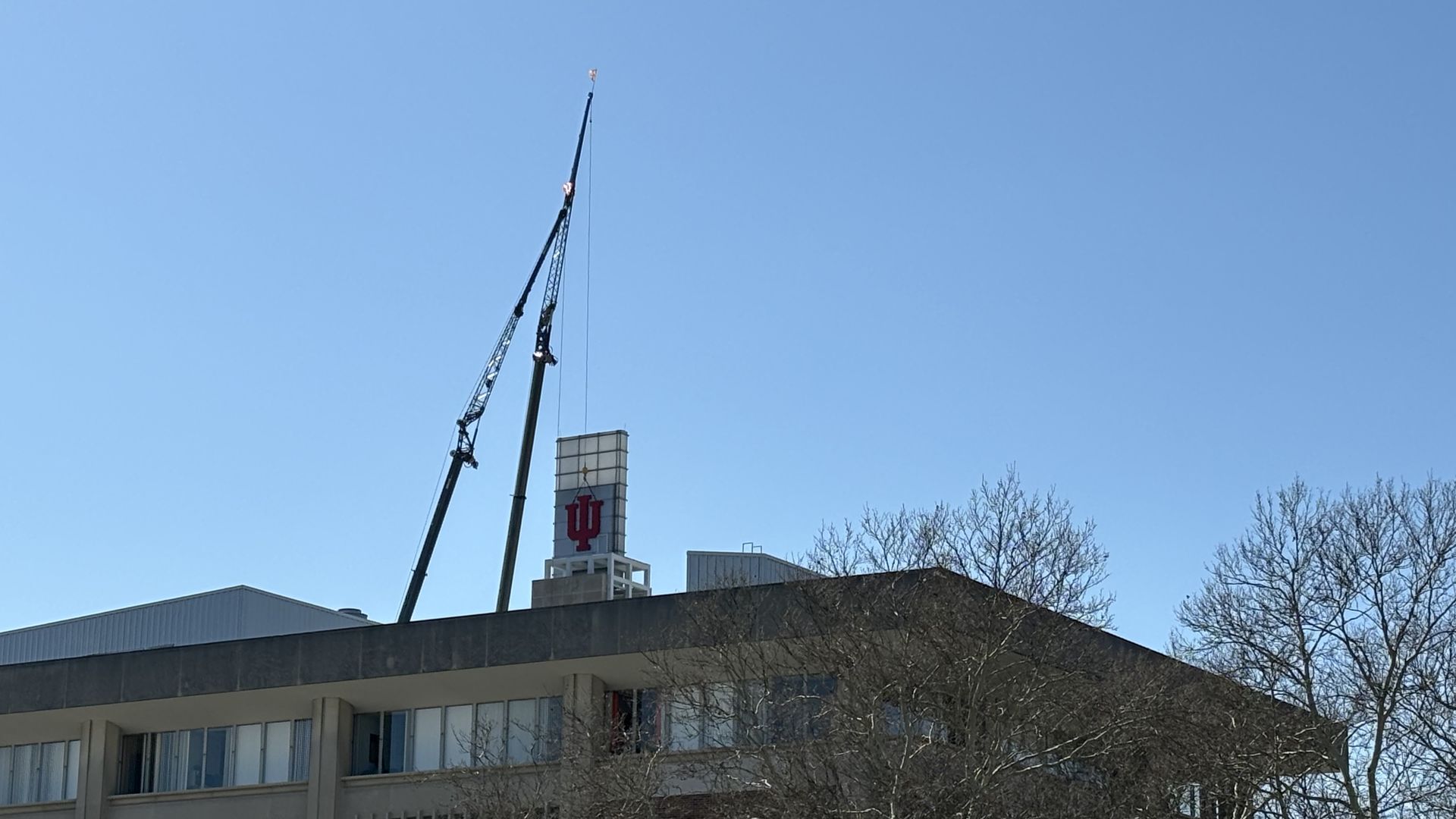 A crane placing an IU sign on the top of a building