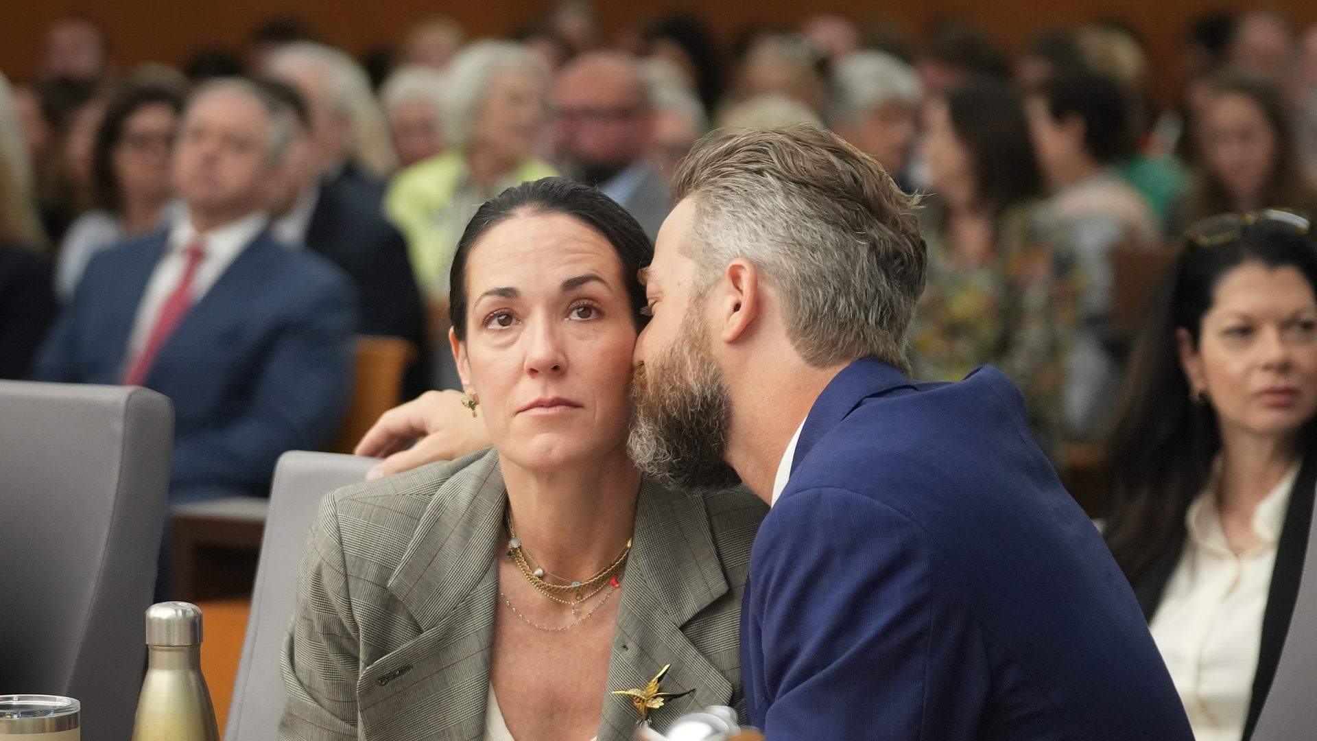 Will Steward leans his face into that of his wife, CiCi Steward, while sitting in a court in Austin. CiCi is looking straight ahead.