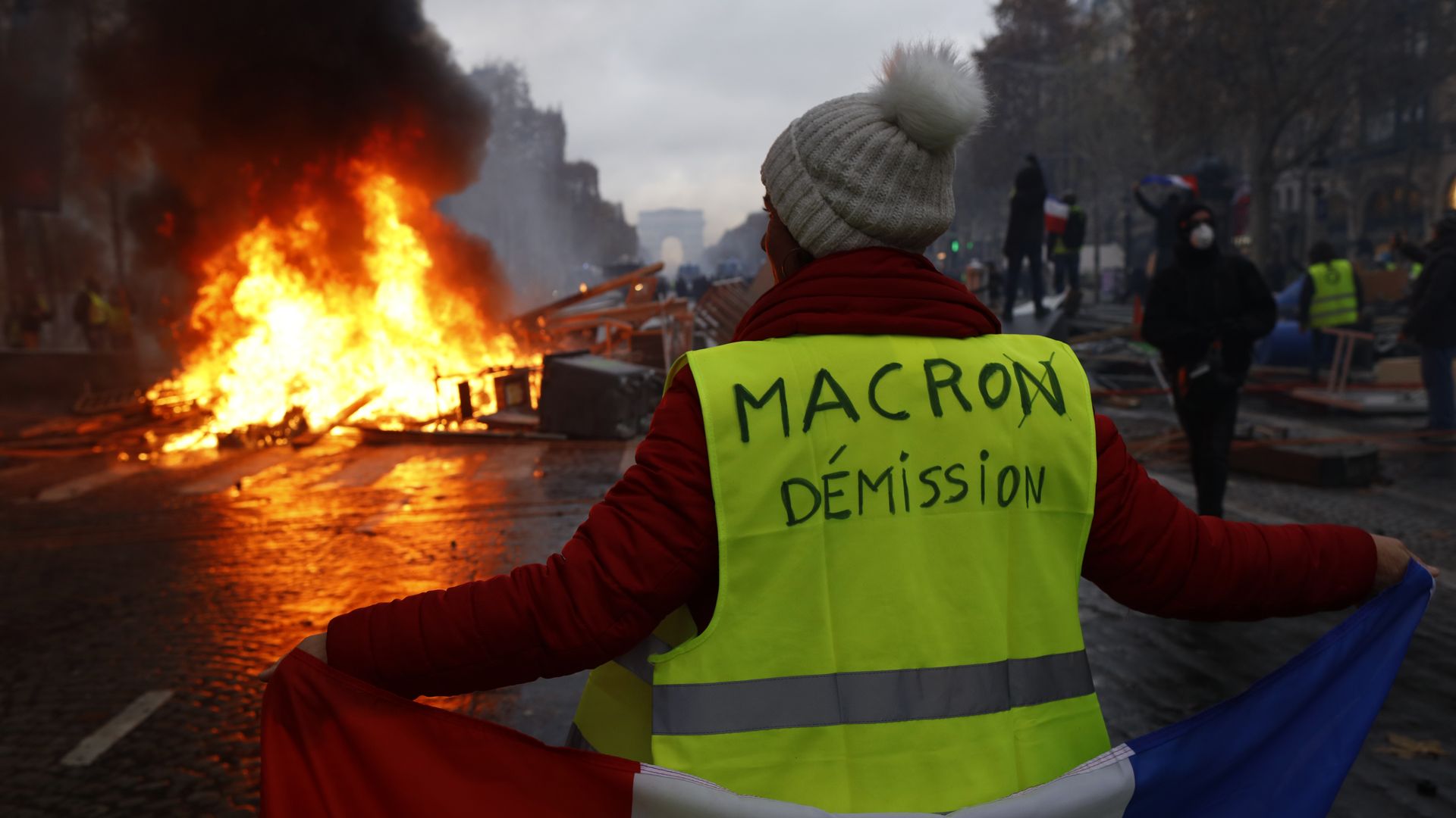 A yellow vest protester with "Macron resign" written on her back.