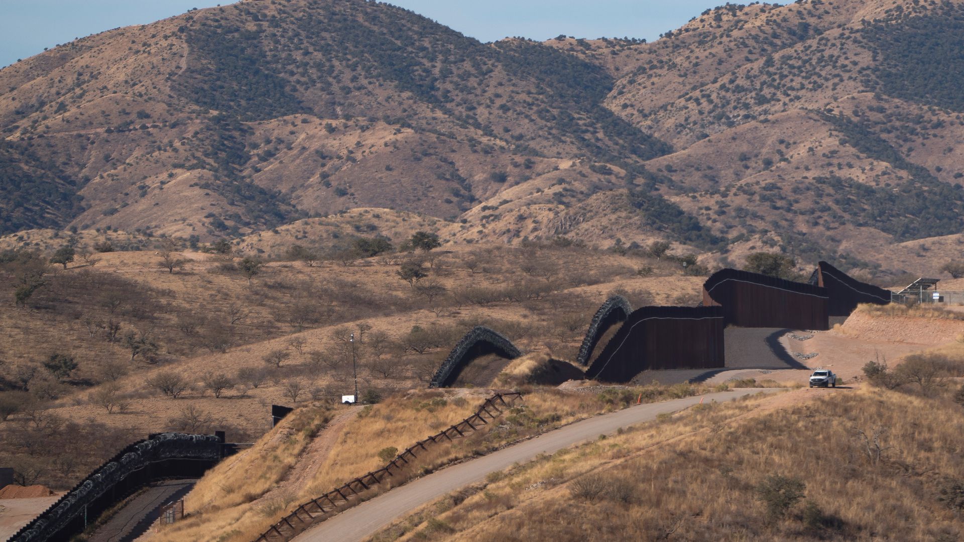 A tall metal fence snakes through the mountains along the United States-Mexico border in Arizona.