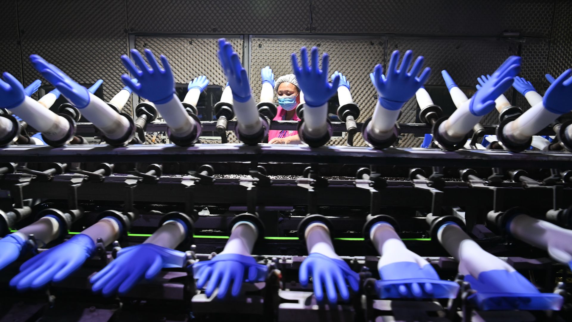 Rows of blue nitrile medical gloves in a manufacturing plant.