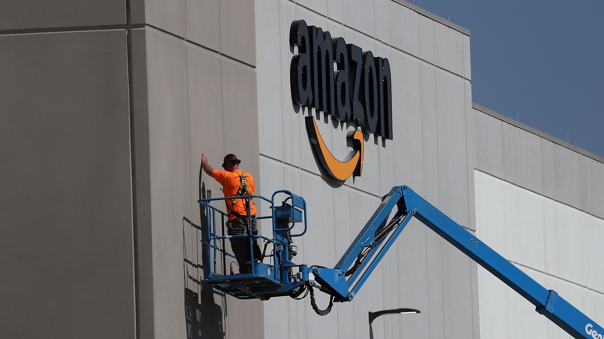 Amazon warehouse with a man on a cherry picker outside. 
