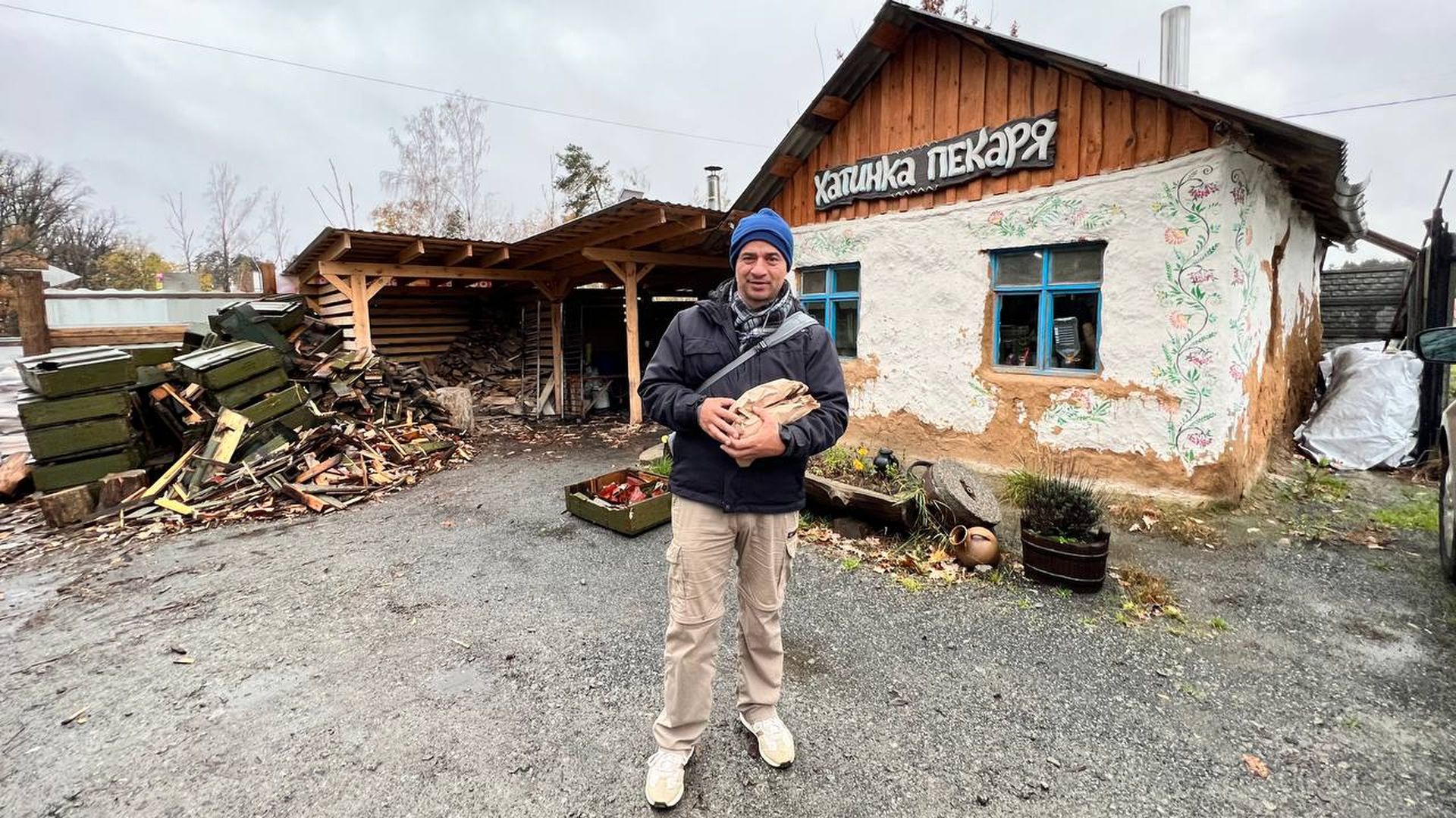 man stands in front of derelict building holding bread 