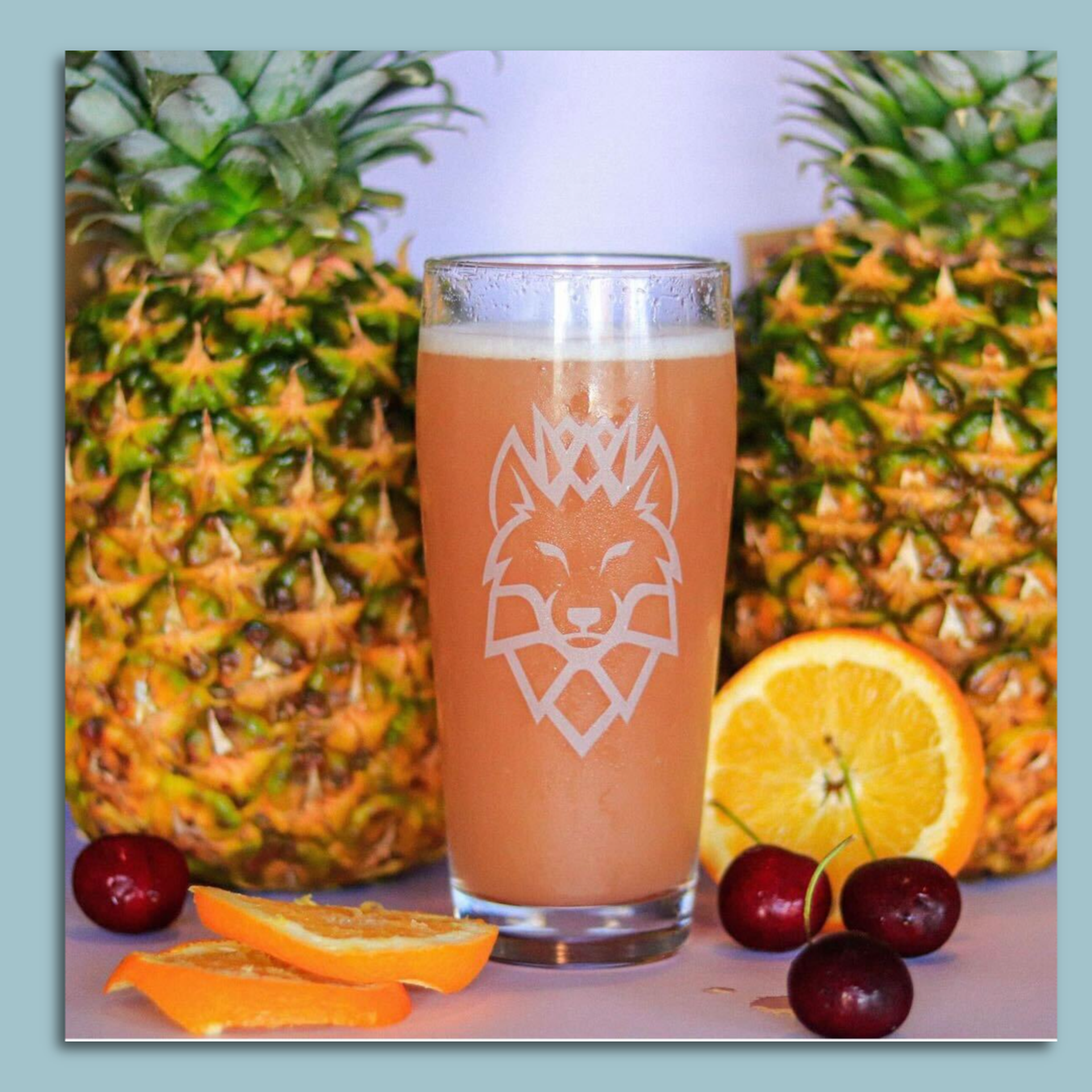 An orange sparkling water surrounded by pineapples, oranges and cherries.