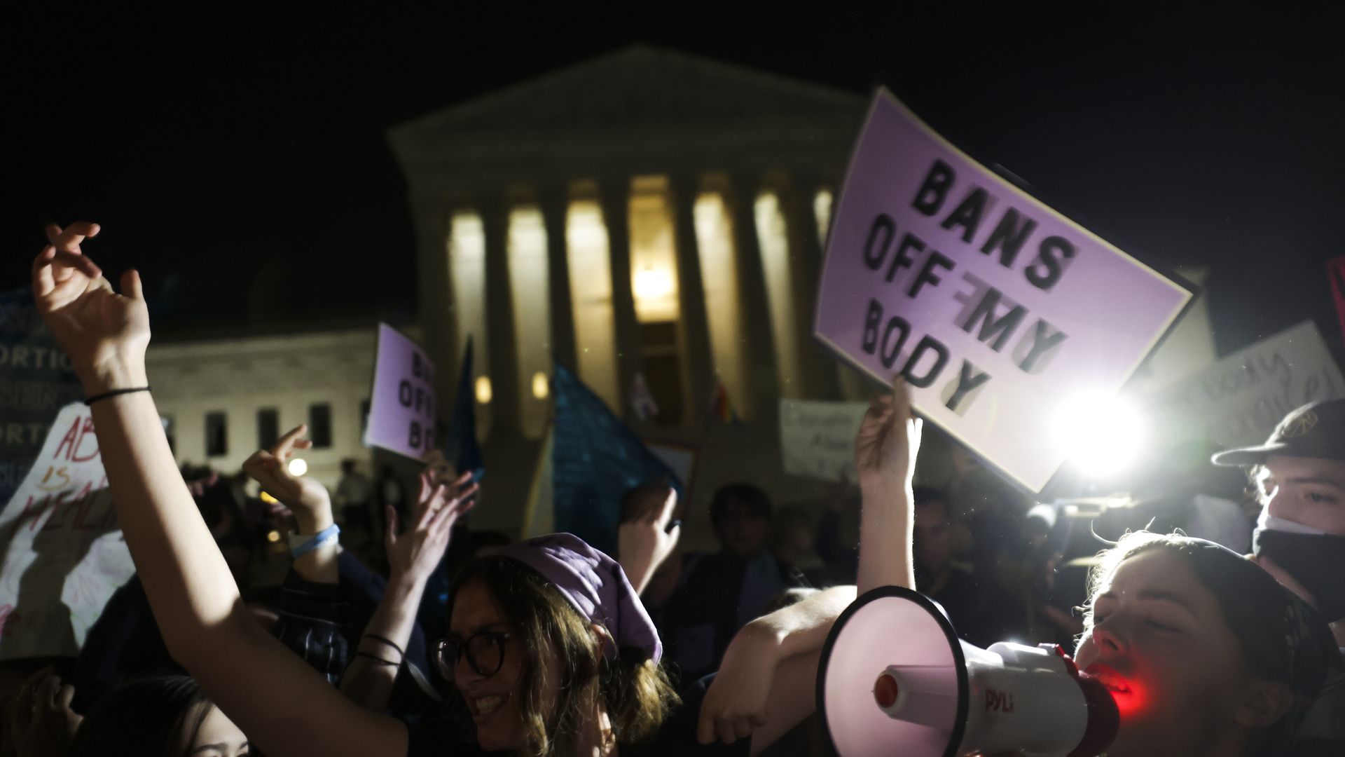 Picture of people standing in front of the Supreme Court at night