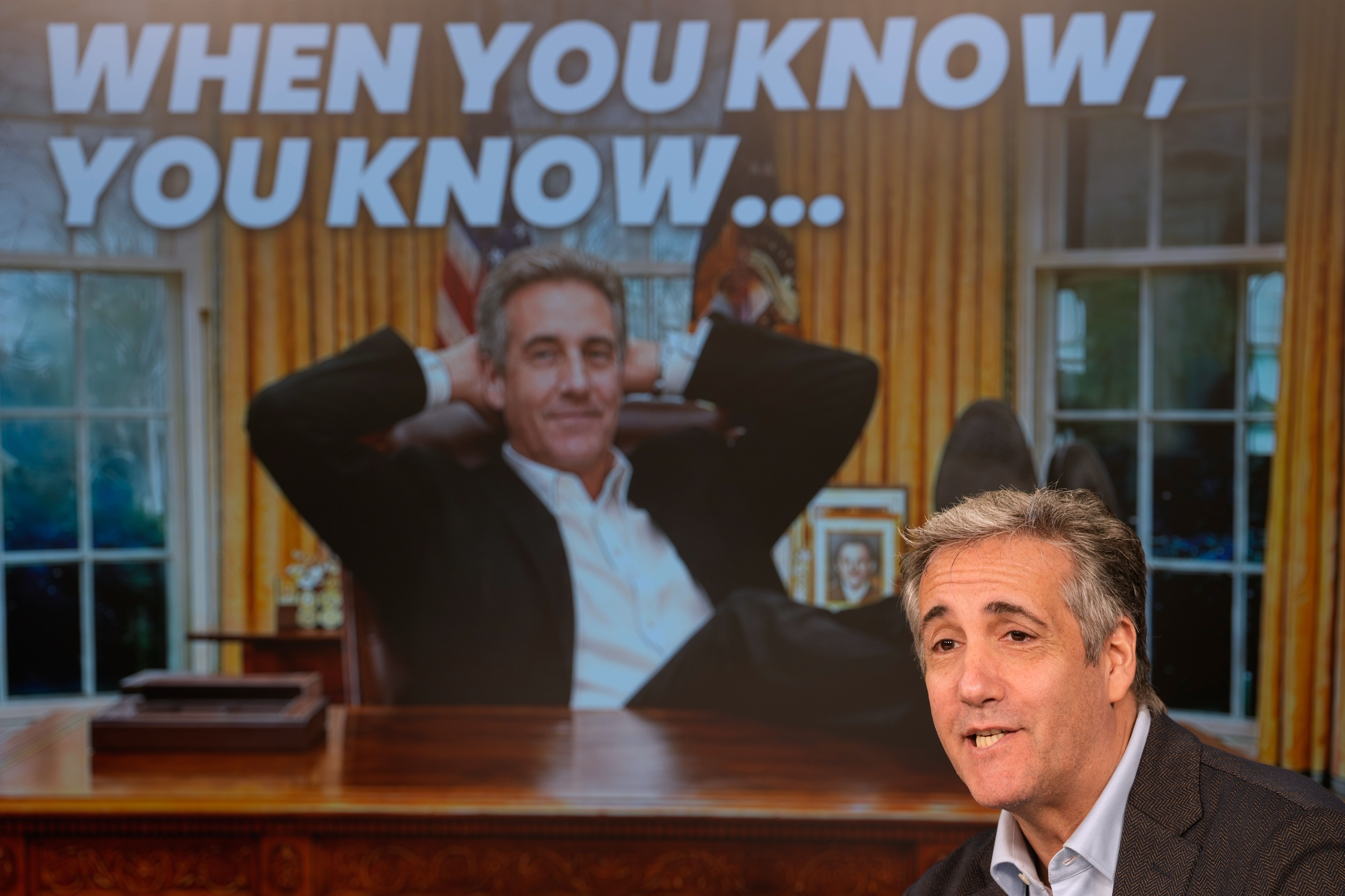 Michael Cohen in front of a backdrop announcing his show
