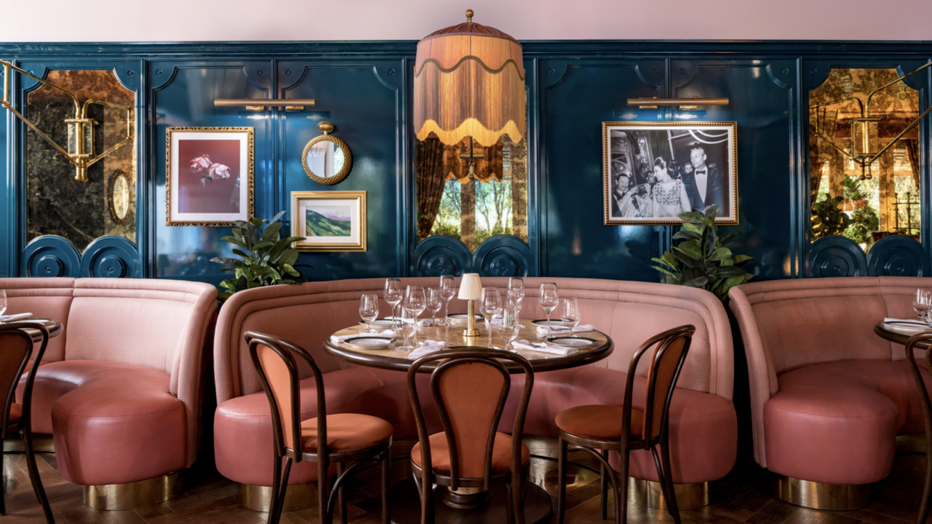 The interior at Contessa, with a pink booth, a round wooden table and blue walls. 