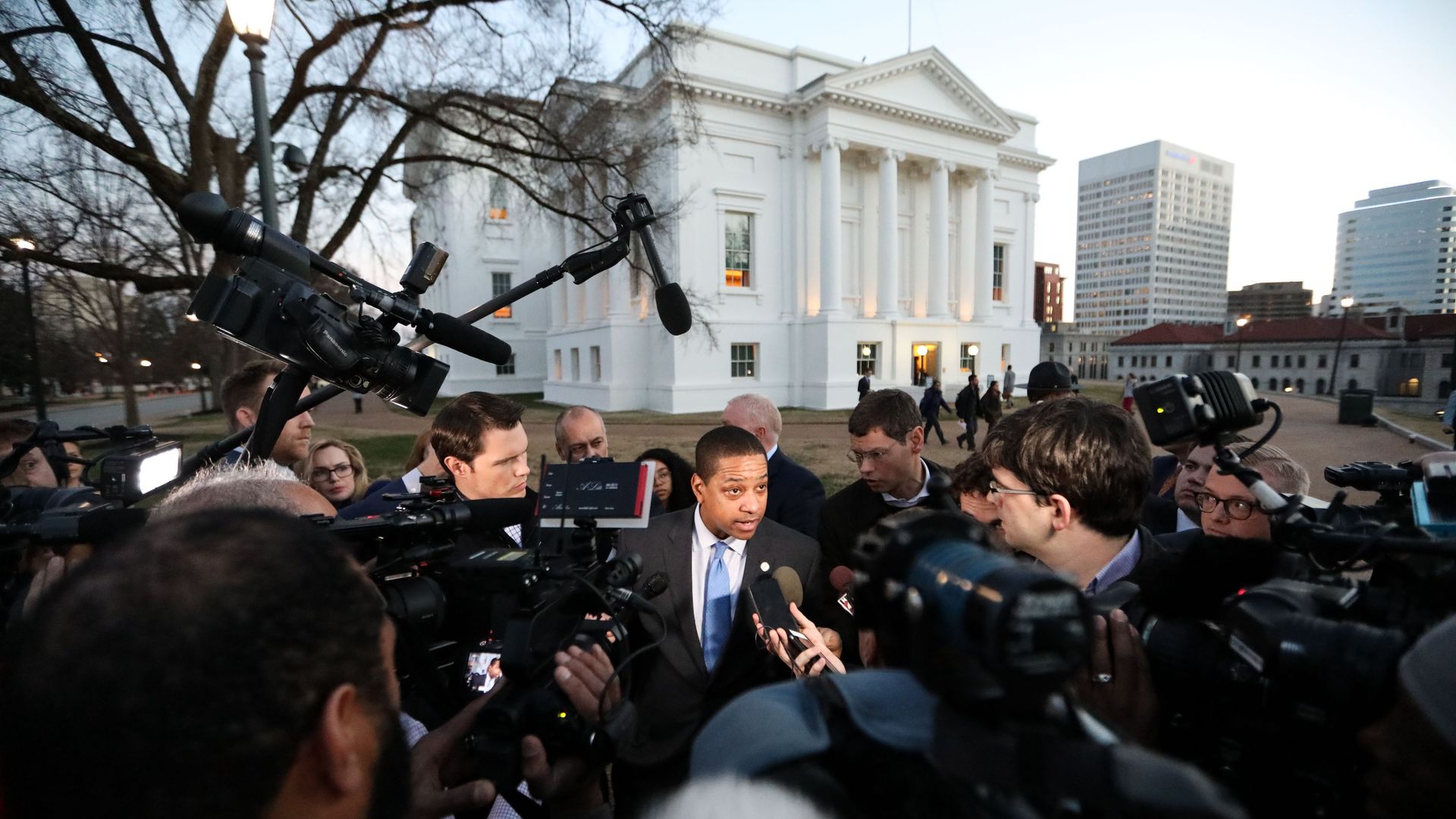 Justin Fairfax surrounded by reporters and mics.