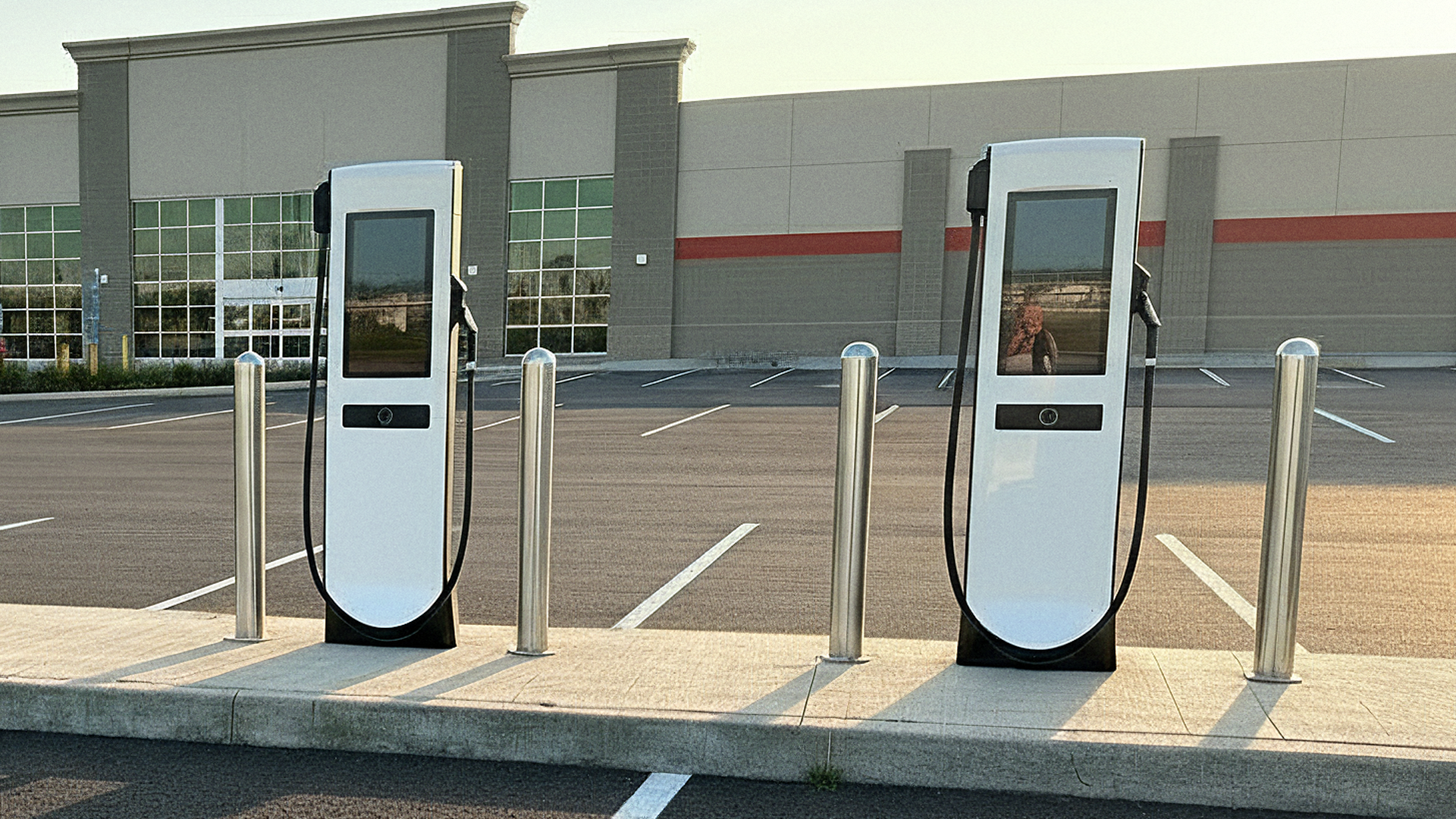 Two Electric Era RetailEdge EV charging stations in an empty parking lot outside an unidentified retail store.